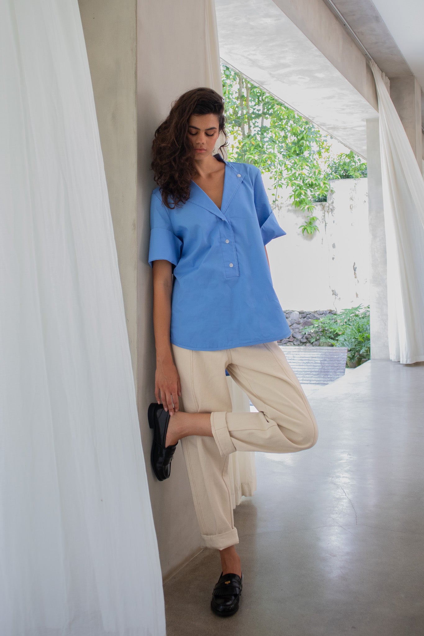 relaxed look, model touching designer shoes, wearing cotton poplin shirt blouse