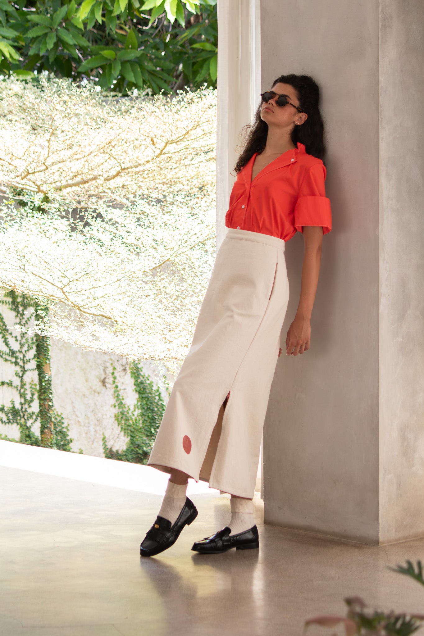 Model looking relaxed leaning up against the wall wearing Designer denim skirt 