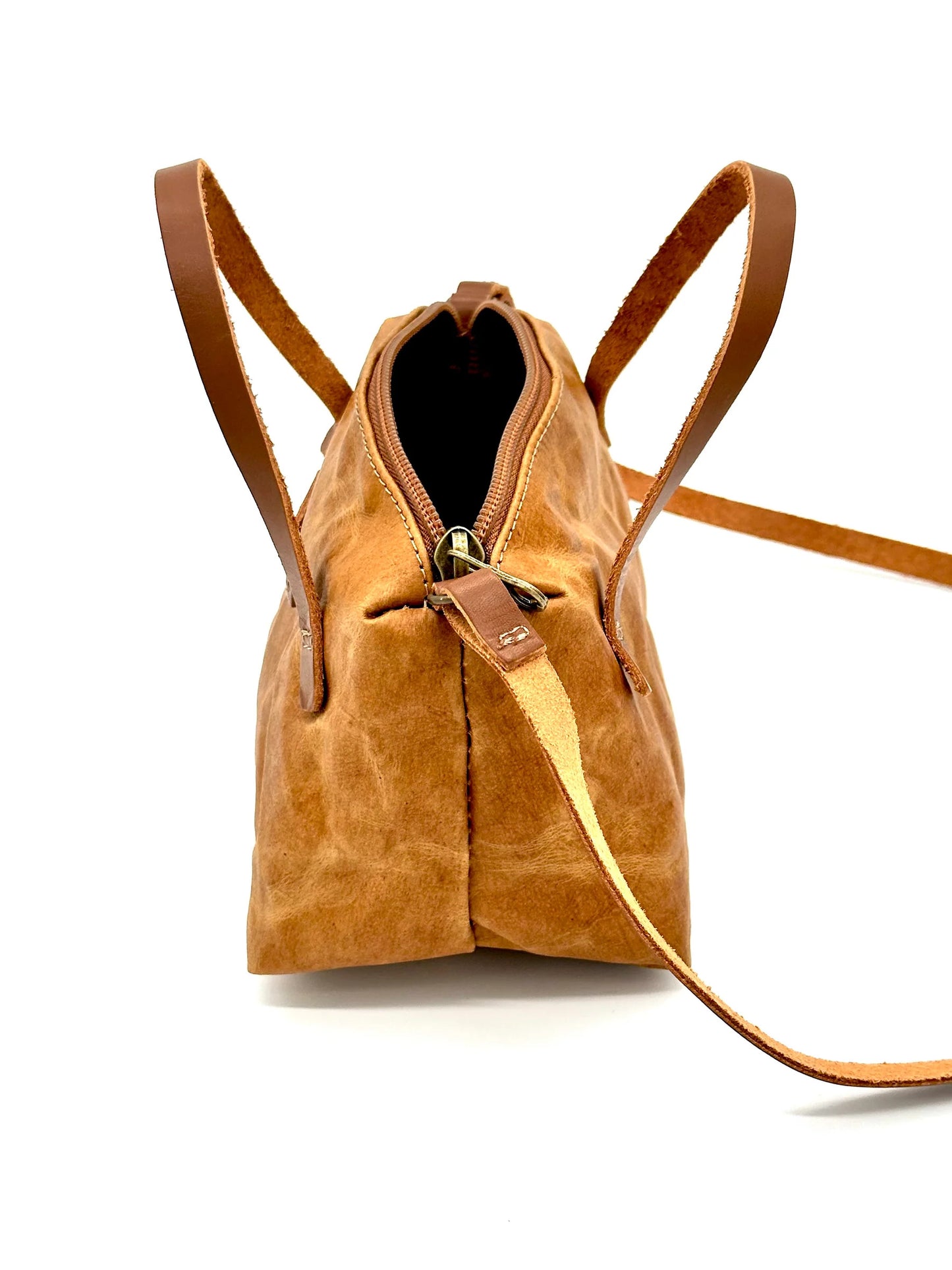 Side view of The Gemmina Bag in tan, showcasing its durable washable paper material, premium leather straps, and secure zipper closure, with a comfortable crossbody strap.