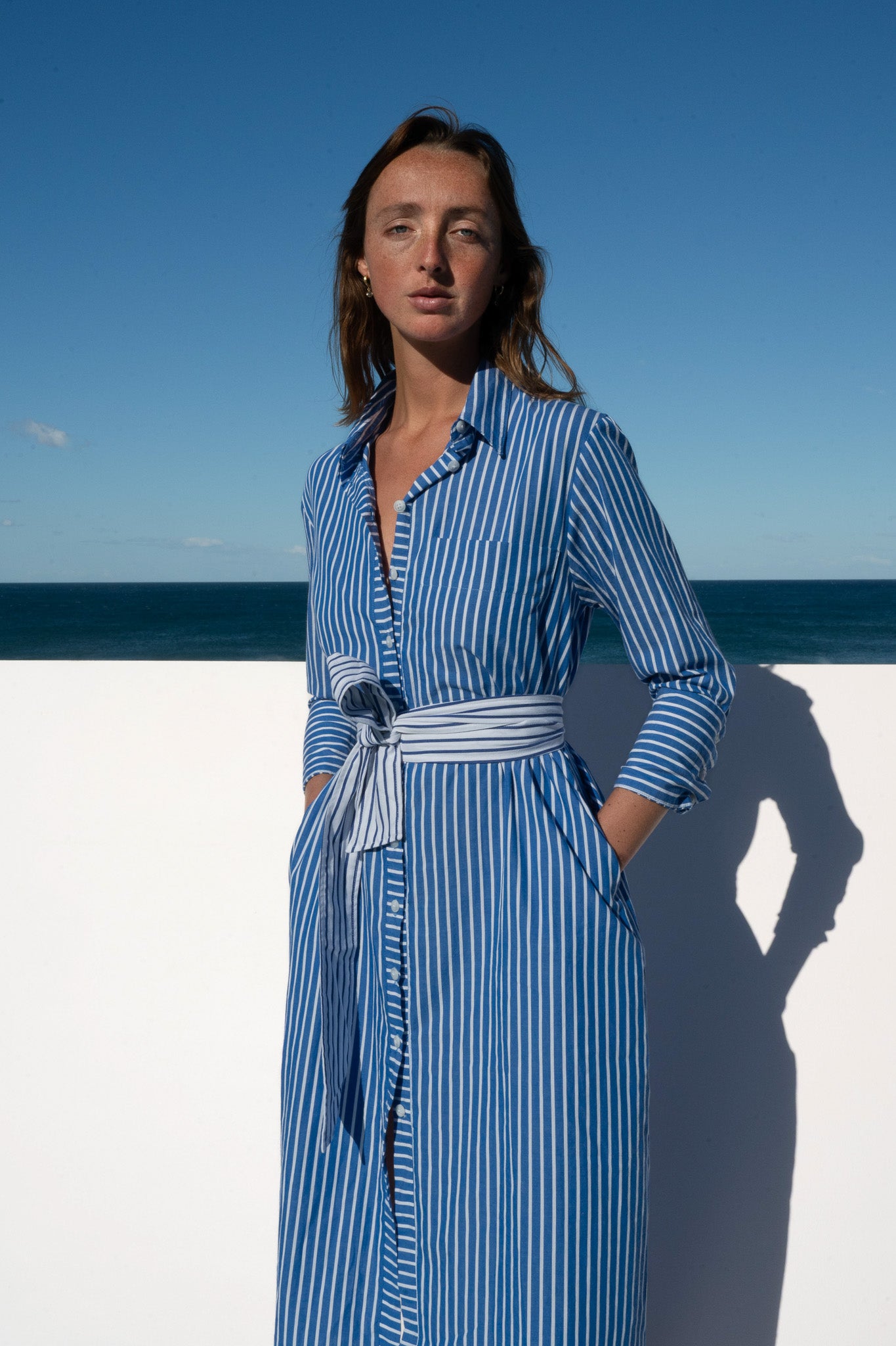 Close-up of Bronte Dress in blue and white stripe showing collared neckline and tie belt.