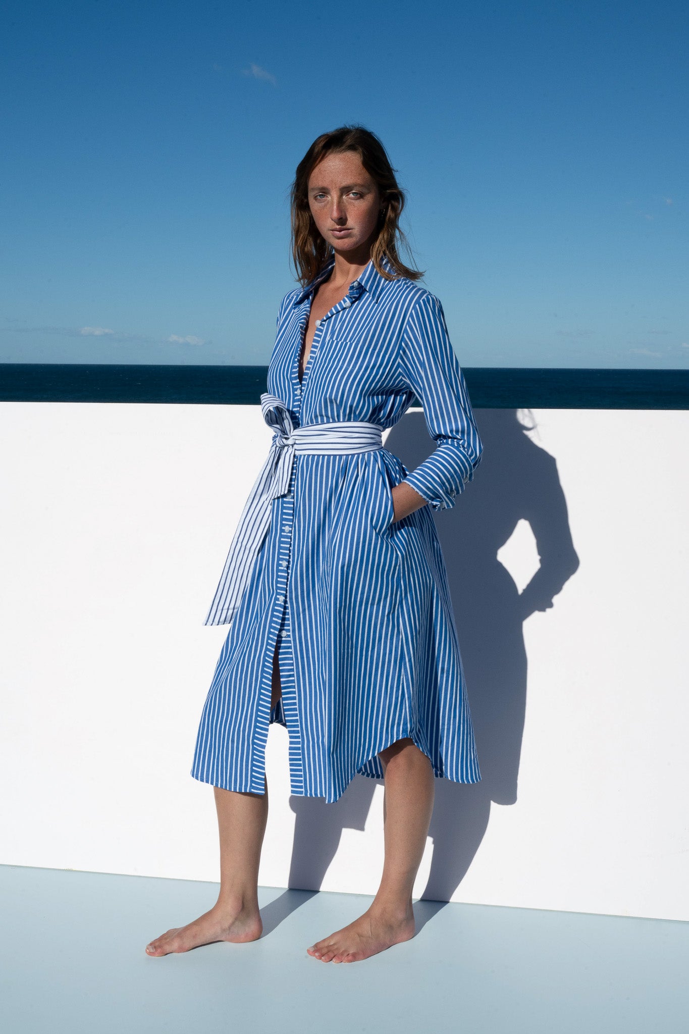 Side angle of the Bronte Dress in blue and white stripe with waist tie.