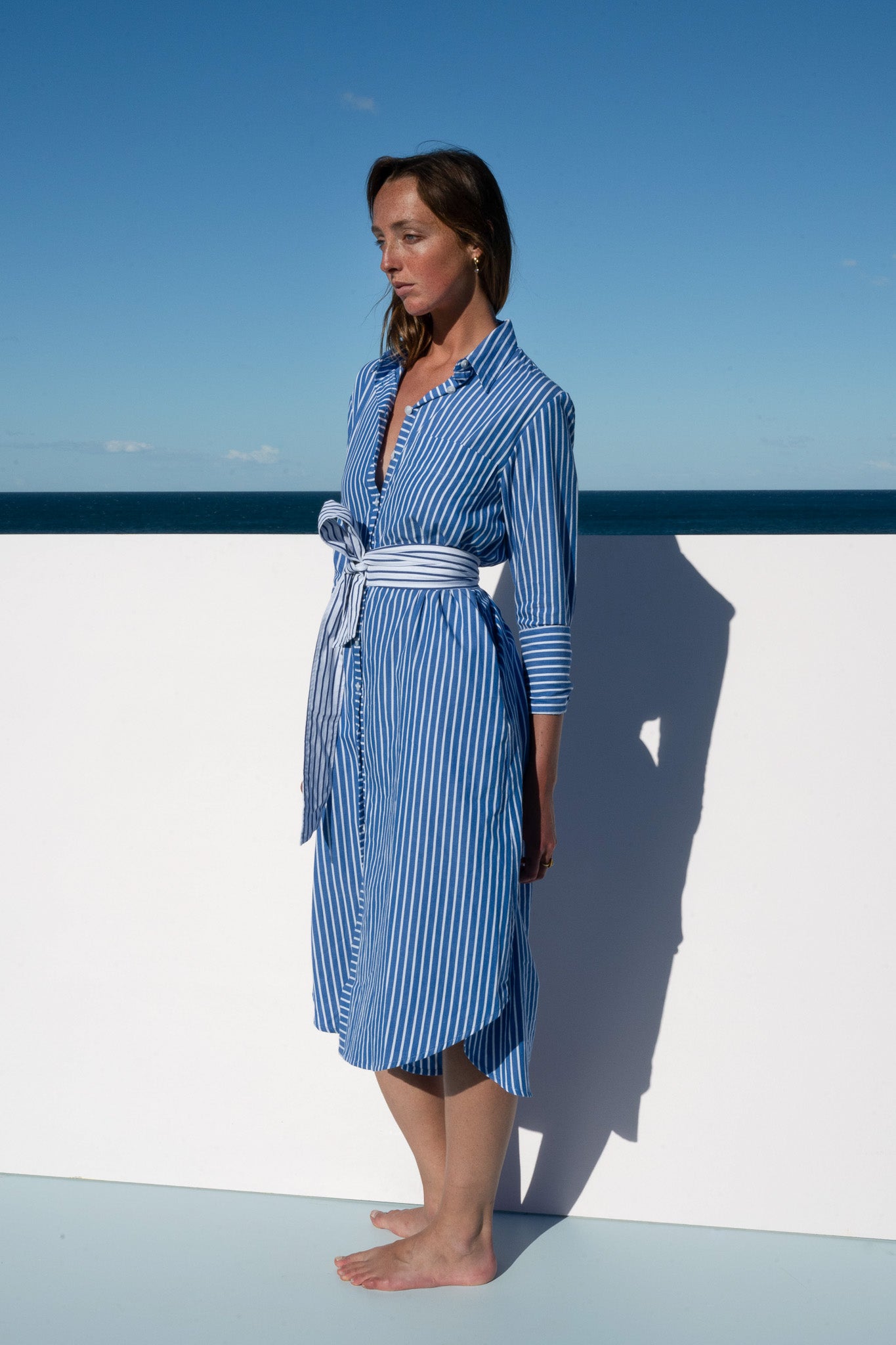 Model in the Bronte Dress blue and white stripe, side profile view