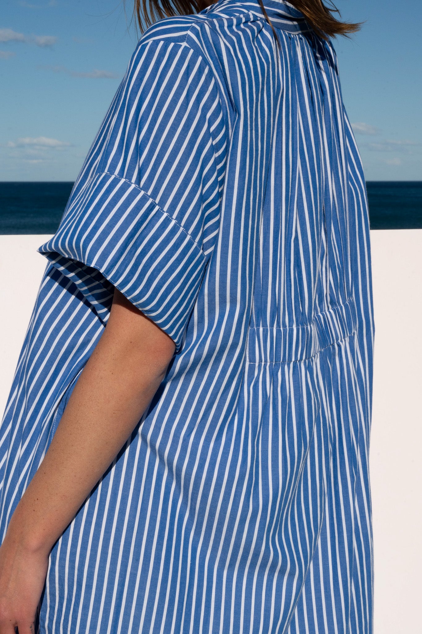 Close-up of wide cuff sleeve and back gathers on the Cabana Dress in cotton blue stripe.