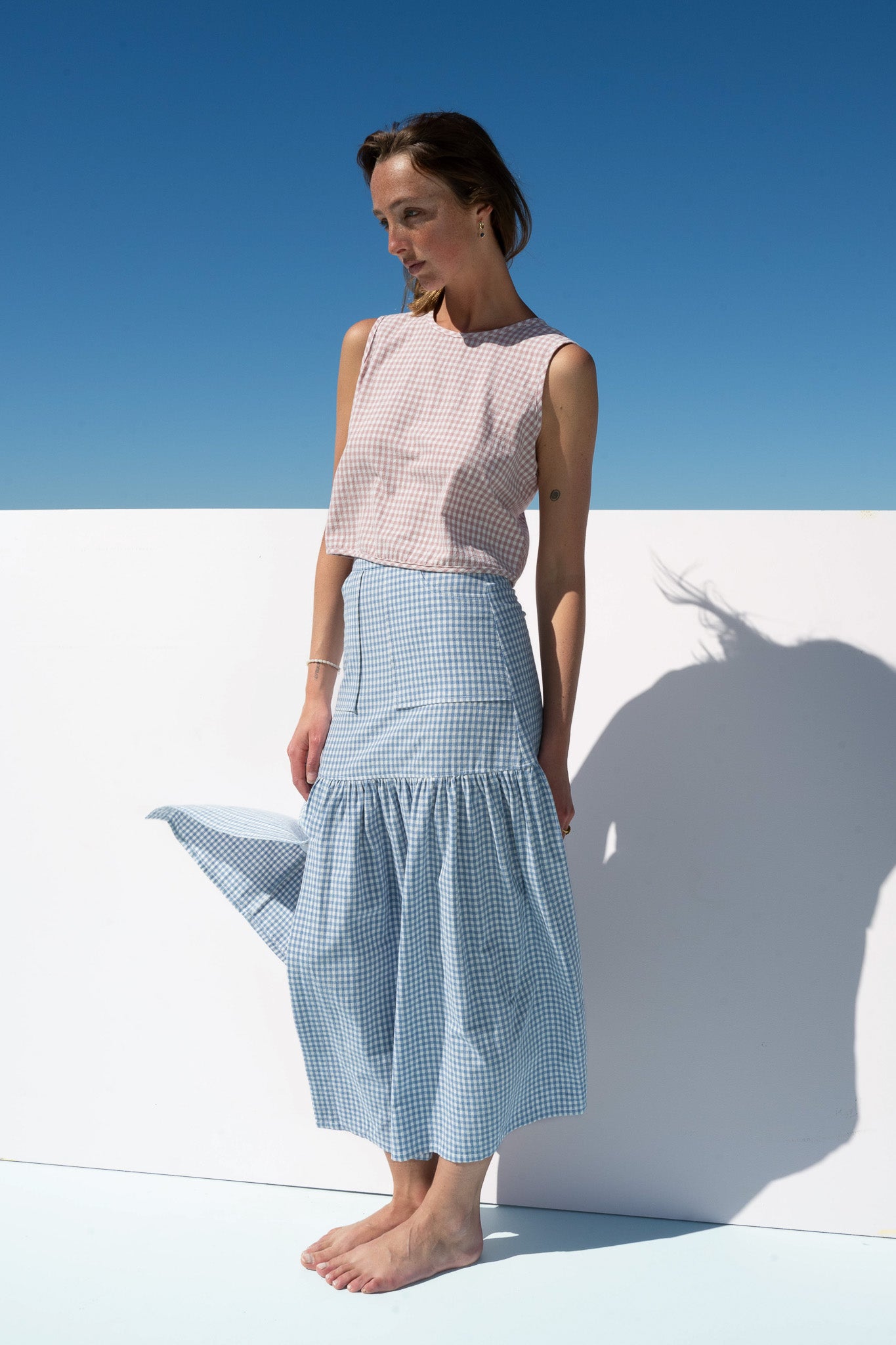 Side profile of Cancan Skirt blue gingham showing movement in hem with blush gingham crop top.