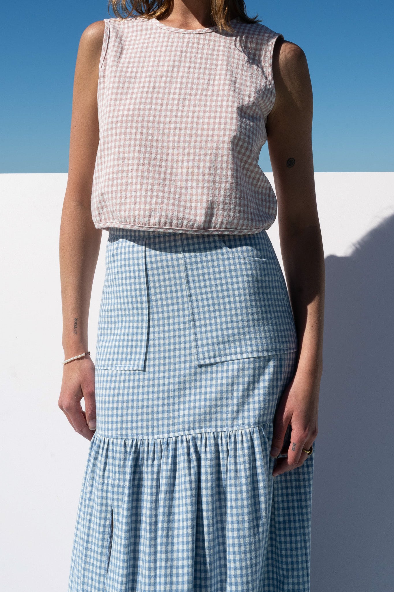 Close-up detail of Cancan Skirt blue gingham pockets and waistband with blush gingham crop top.