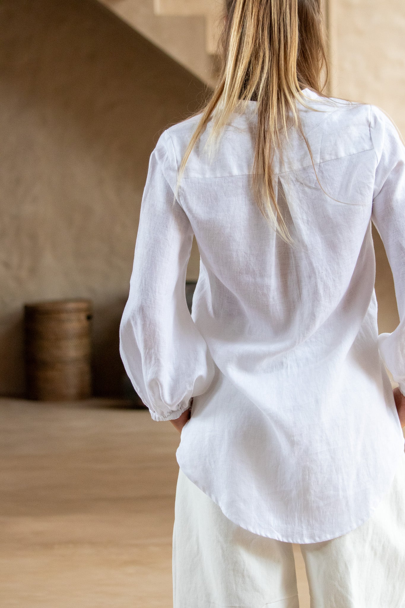 Back view of the Coconut Blouse in white, highlighting the curved hem and soft drape of the organic linen.