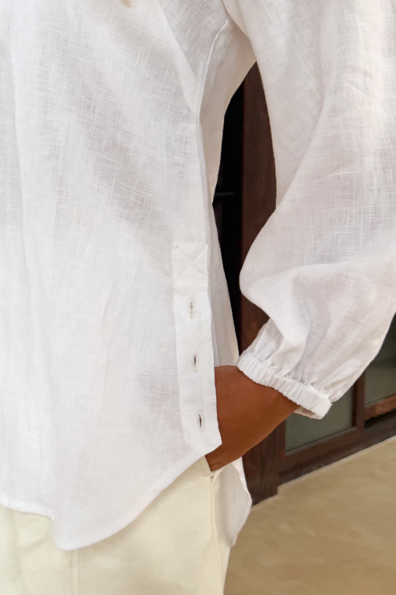 Close-up of Coconut Blouse in white highlighting side tab with button detail and gathered sleeve cuff.