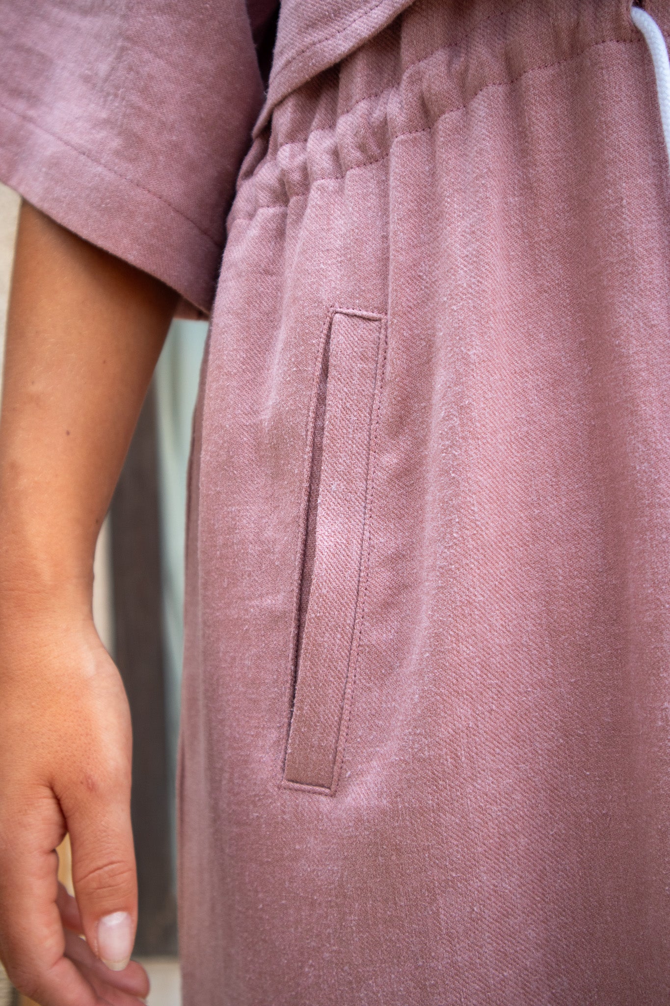Side pocket close-up of Iconica Dress in dusty pink, showcasing the texture and craftsmanship of the linen fabric.