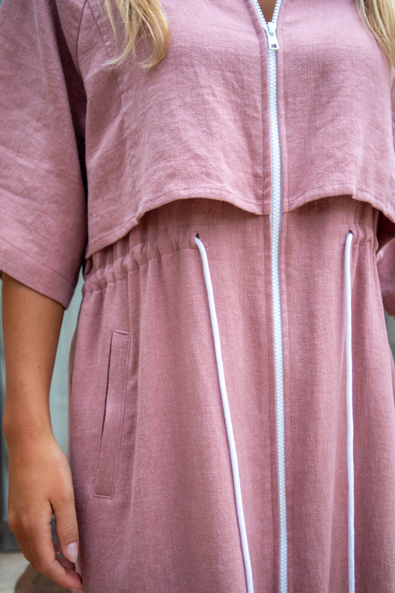 Close-up of the Iconica Dress waist with gathered elastic and white drawcord on dusty pink organic linen.