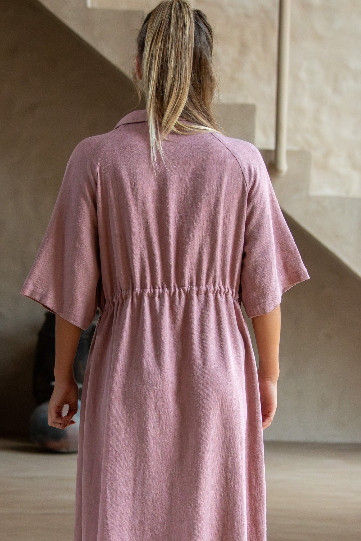 Back view of Iconica dress showing elasticated waist detail and soft linen fabric in dusty pink