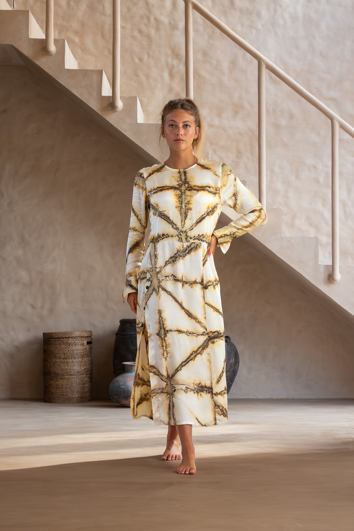 Front view of Maggie Dress in Earth Shibori with long sleeves, side buttons, and flowy silhouette indoors