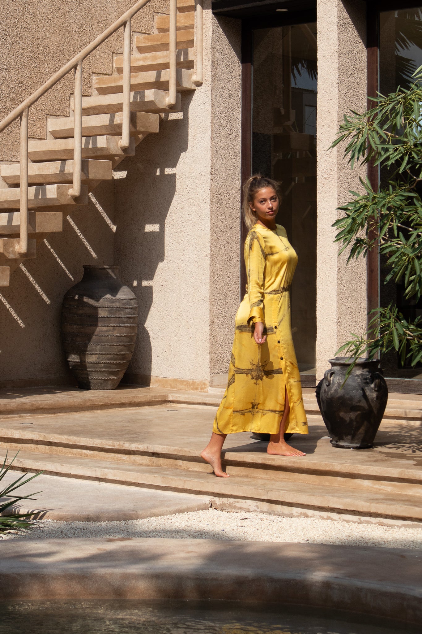 Model in Maggie Dress Mango Shibori walking barefoot near stairs with side button detail
