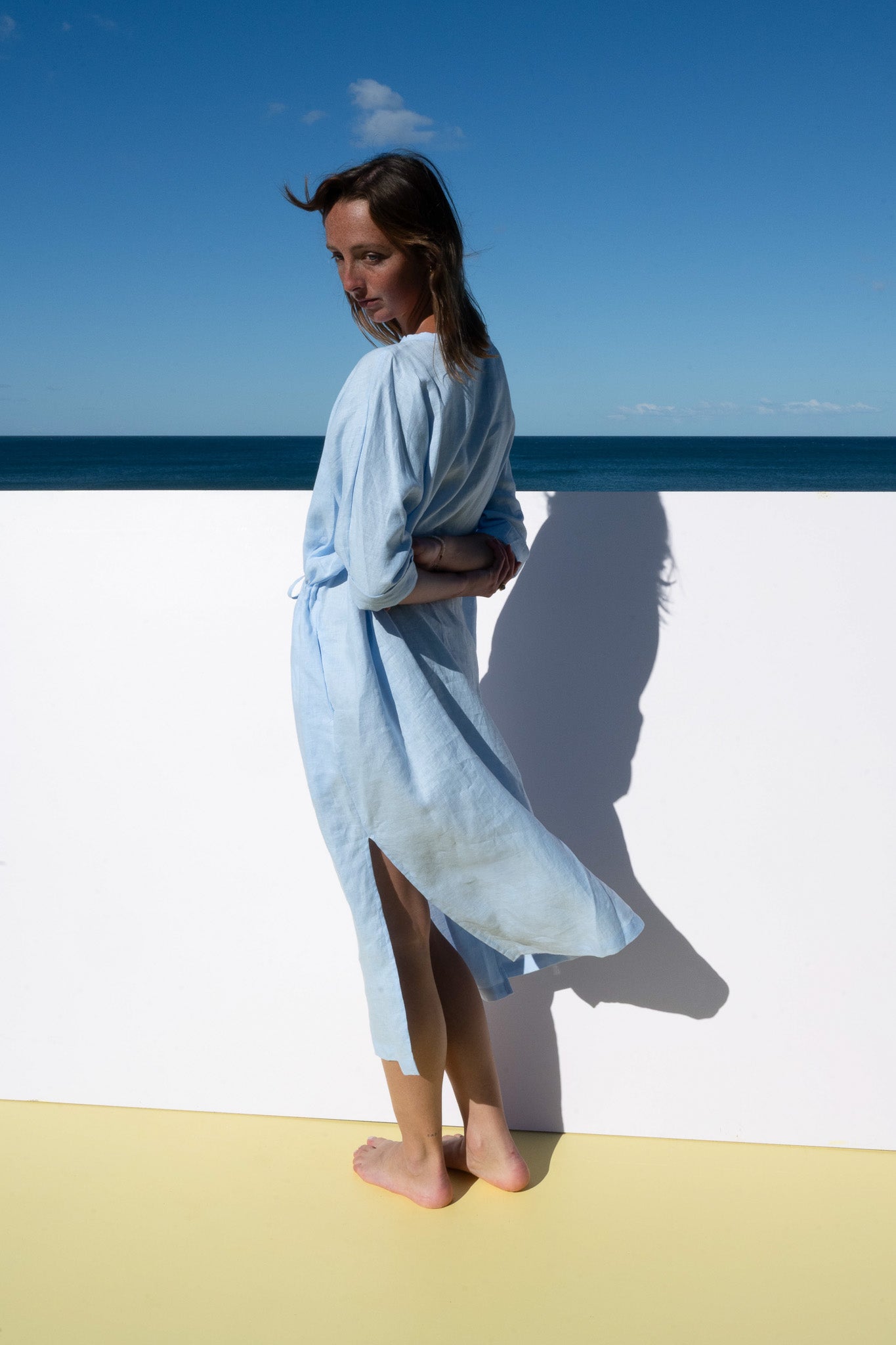 The Moments Dress in corn flour blue linen, side view highlighting slit detail and relaxed drape.