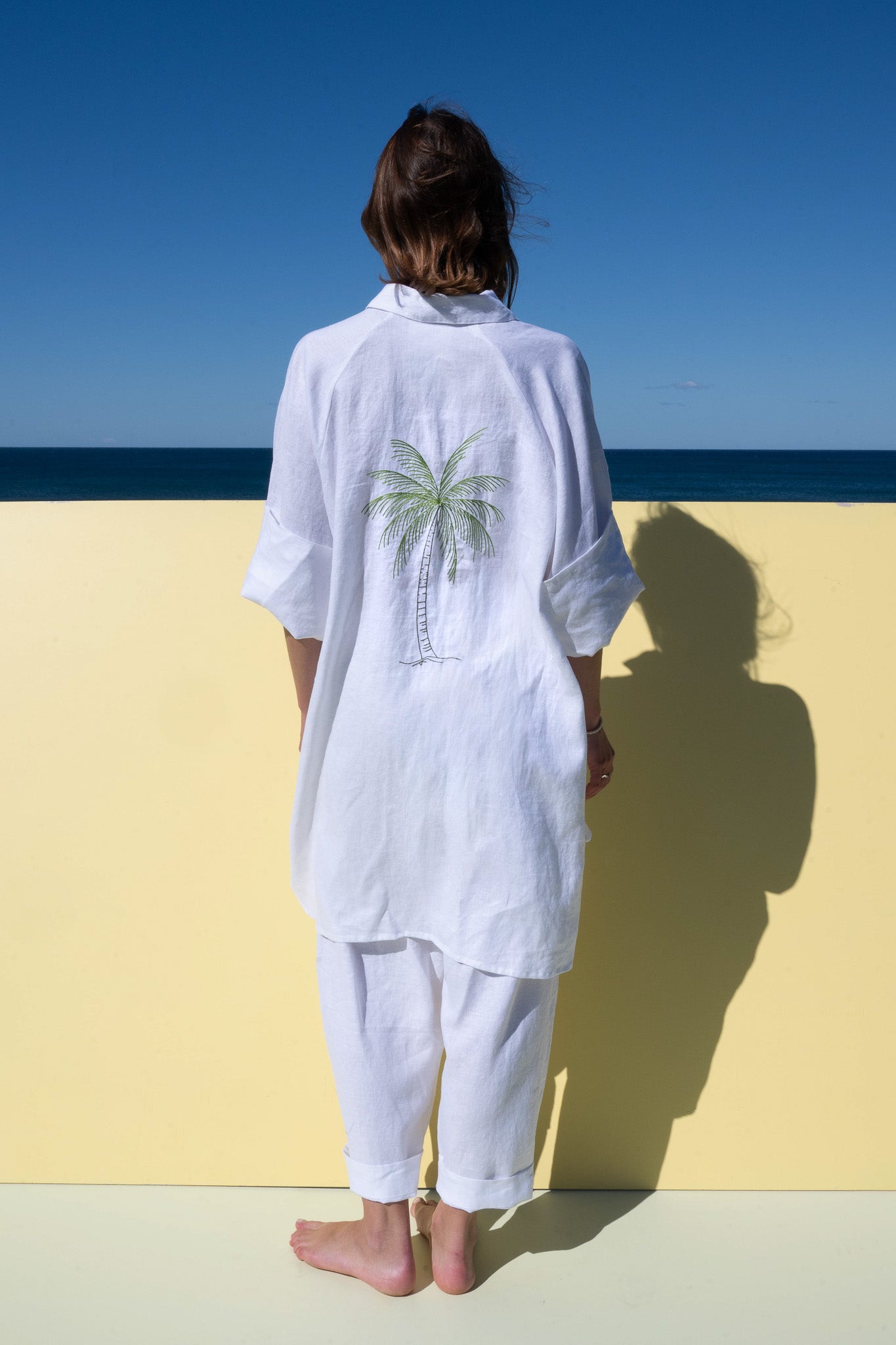 Oceanic Shirt Dress in white linen – full length back shot showcasing embroidered palm detail