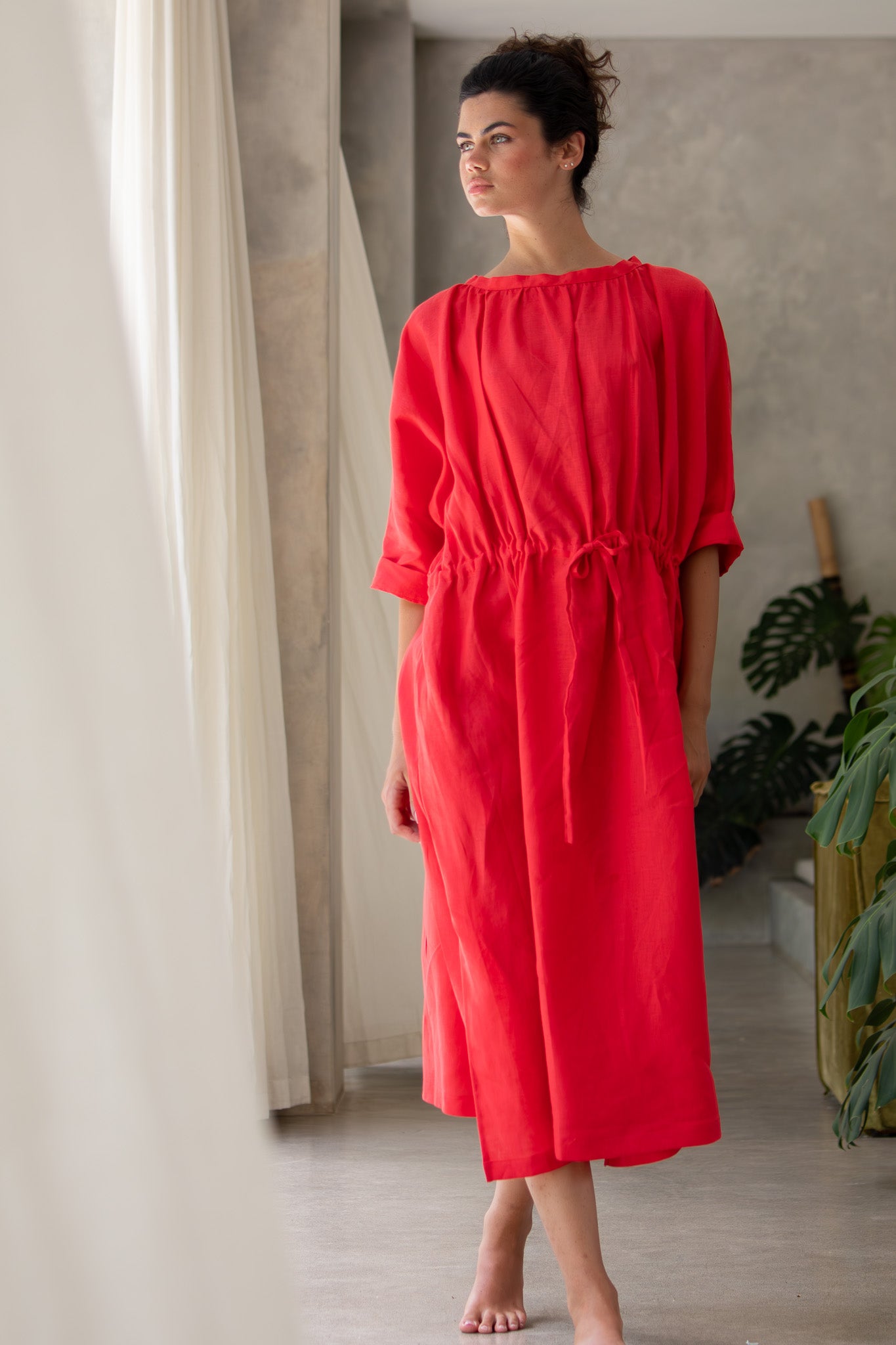 Red linen dress made using luxury fabric in Australia, Model standing gazing off to the right 
