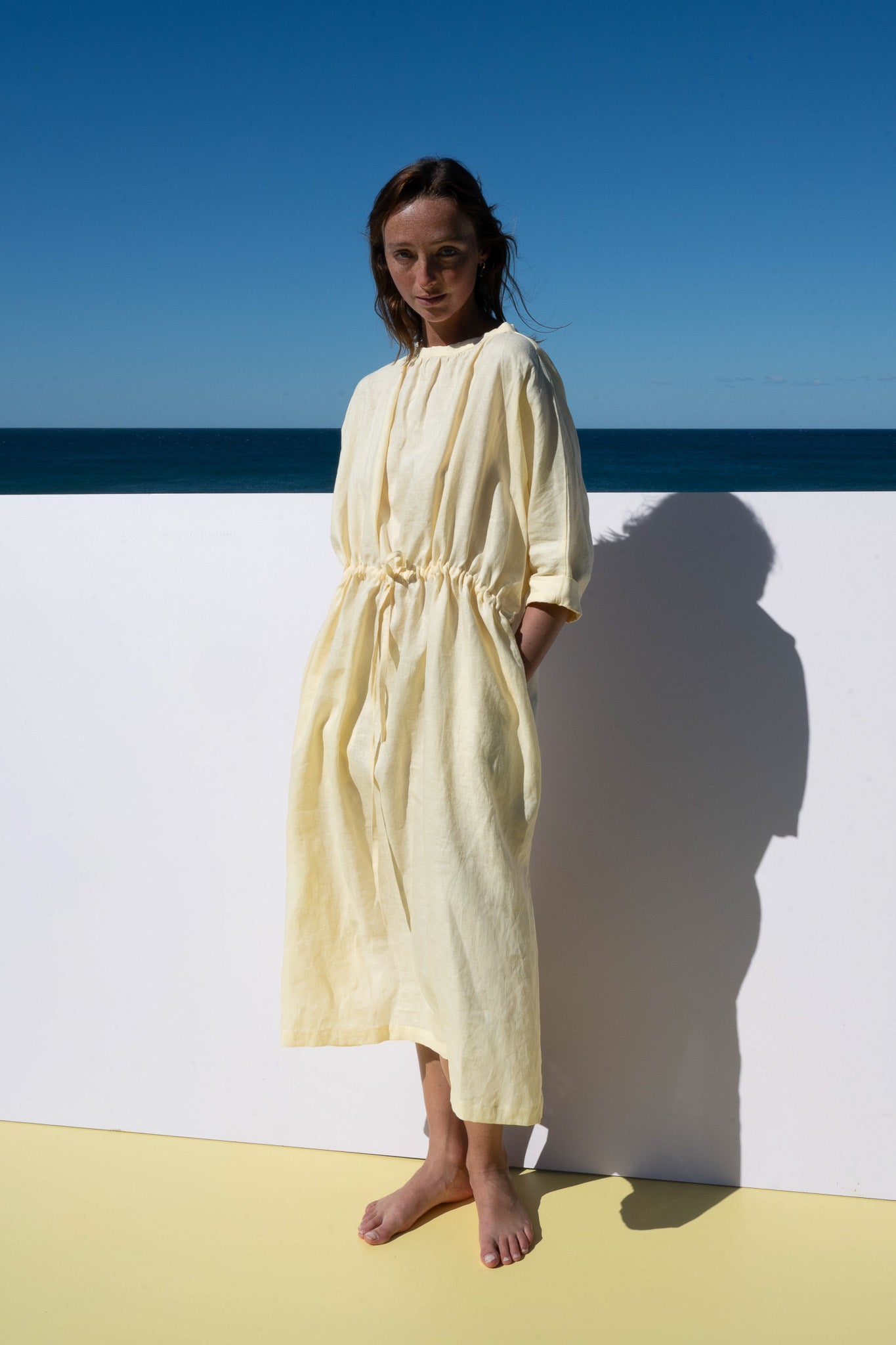 The Moments Dress in yellow linen – front angle with drawstring waist and hidden pockets