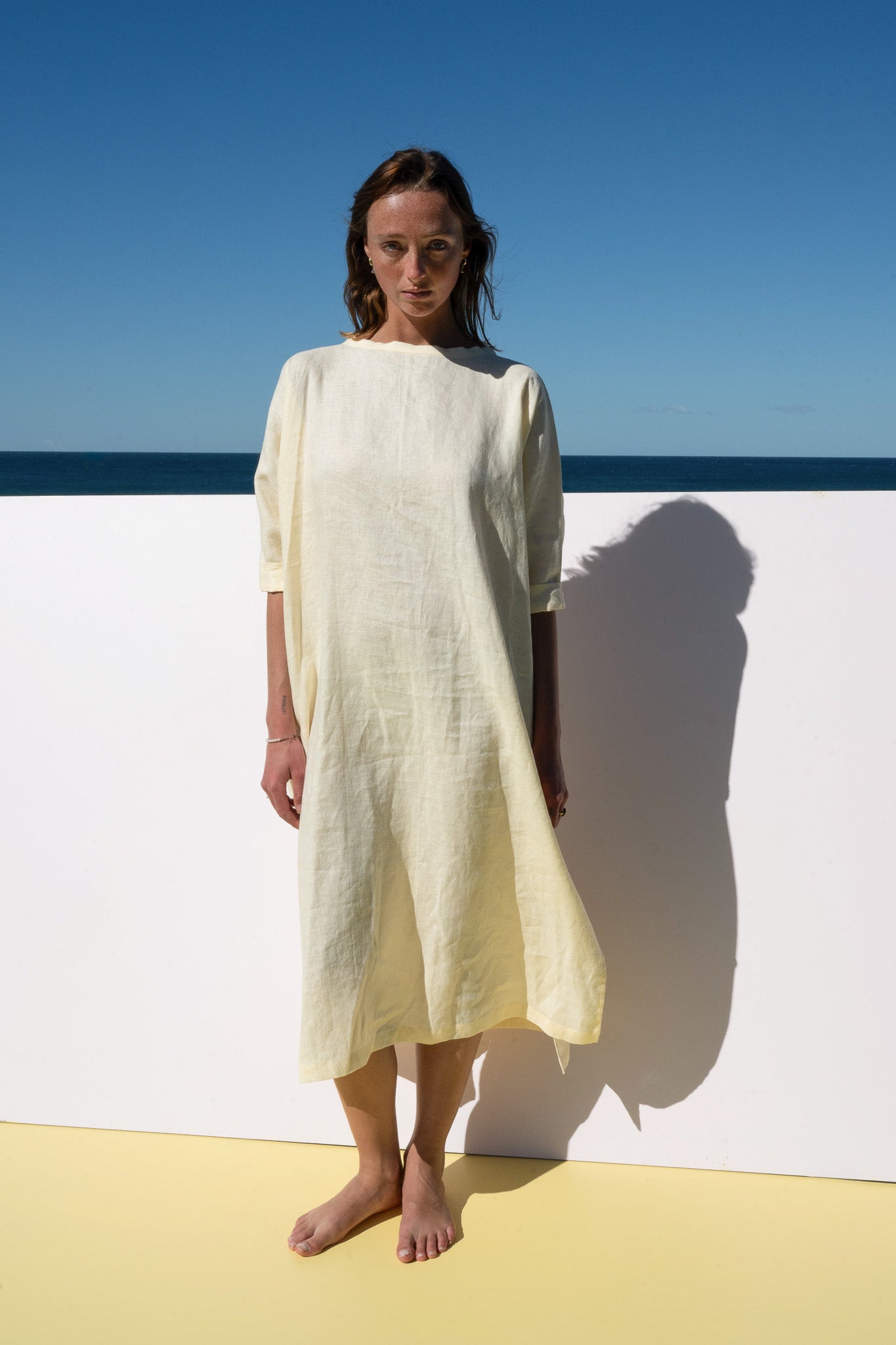 The Moments Dress in yellow linen – straight front view showing minimalist silhouette
