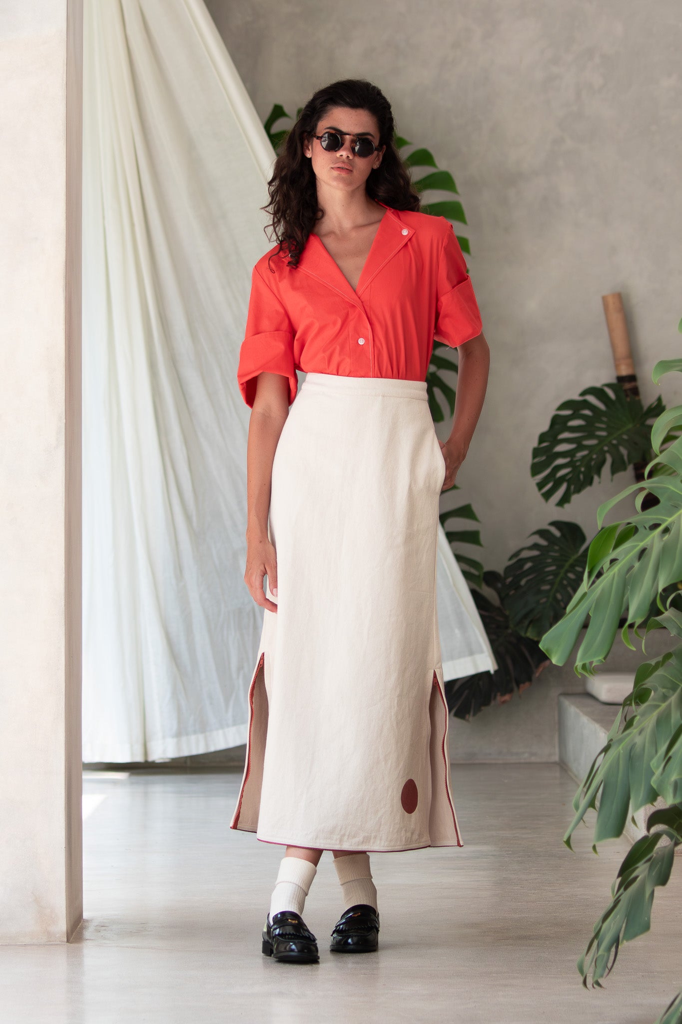 Model wearing Designer denim skirt with side zip details with curtain blowing in the background 