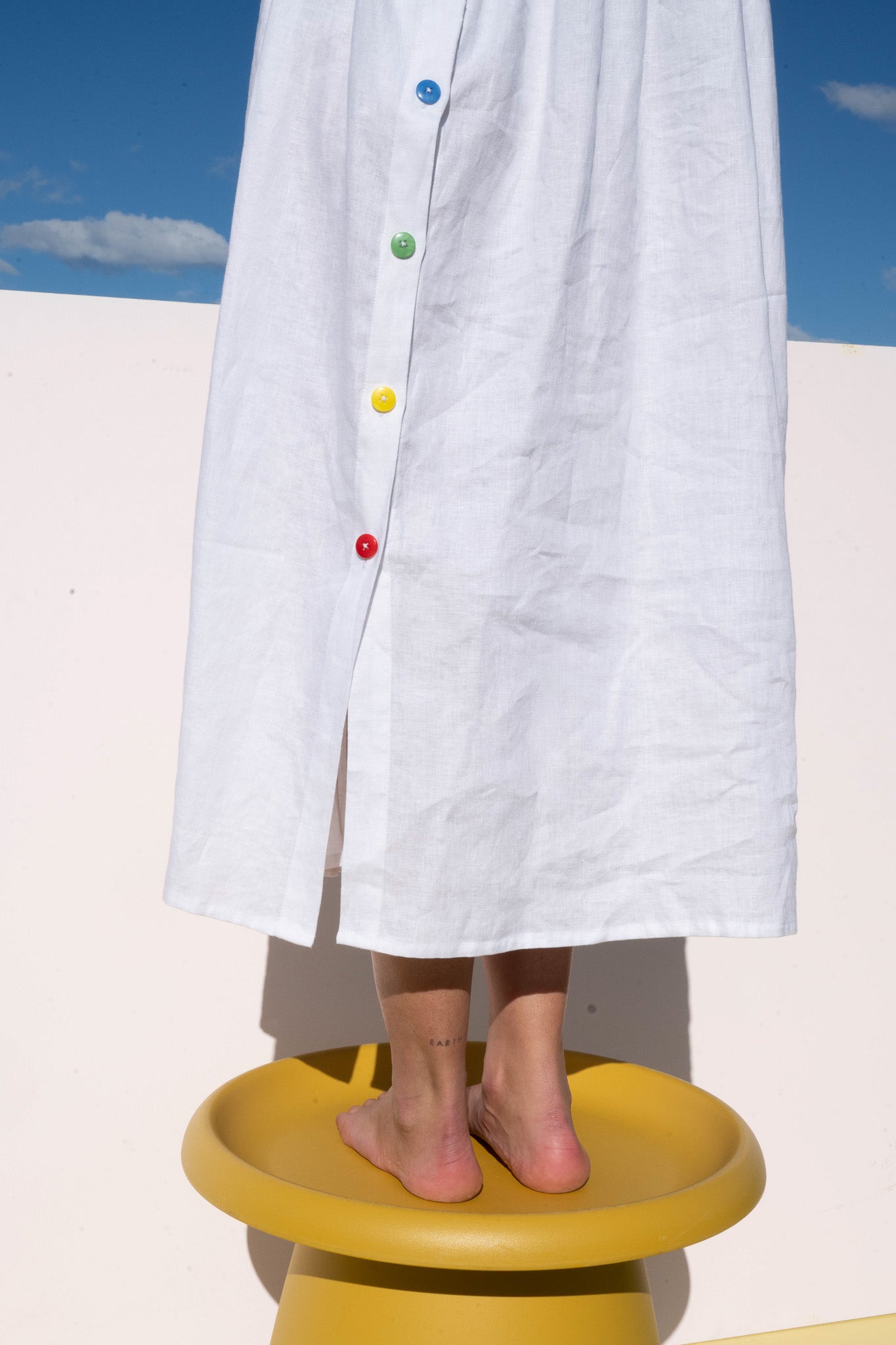 Hemline detail of the Wonka Sleeveless Dress showing rainbow-colored buttons