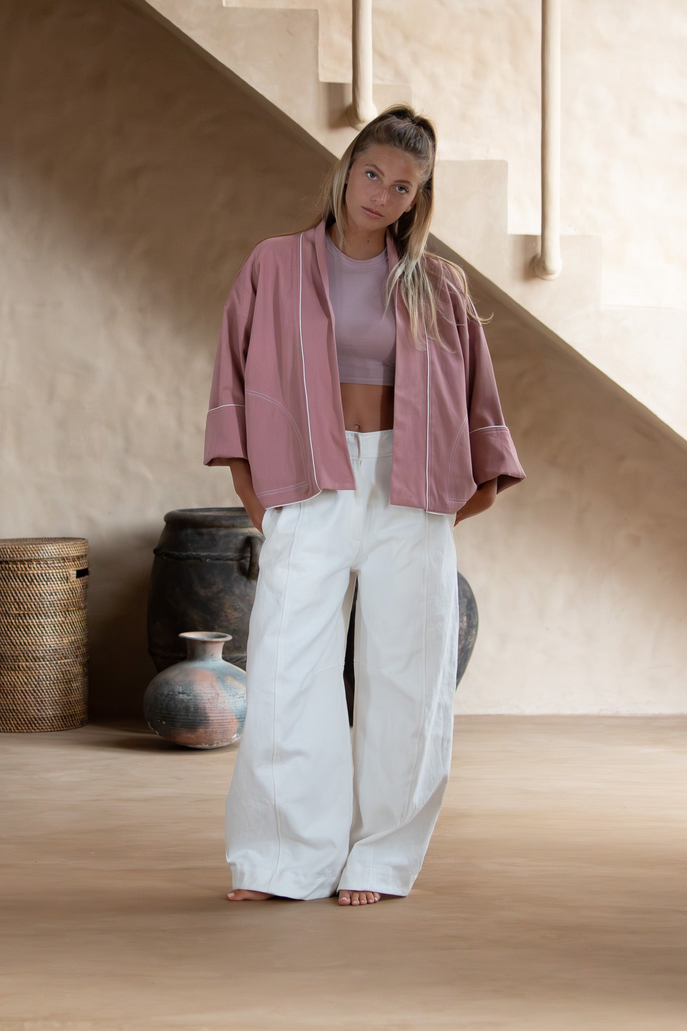 Woman in the Yoko Kimono Shortie in Dusty Pink standing in a minimalist indoor setting, showcasing the oversized silhouette and open front.