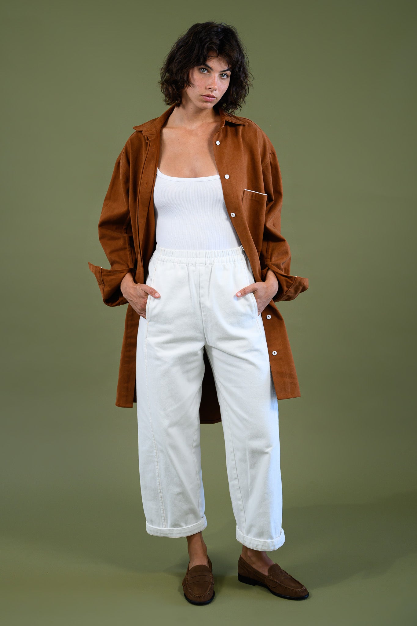 Front full body view of Caramel cotton canvas denim shirt coat worn open with hands in pockets