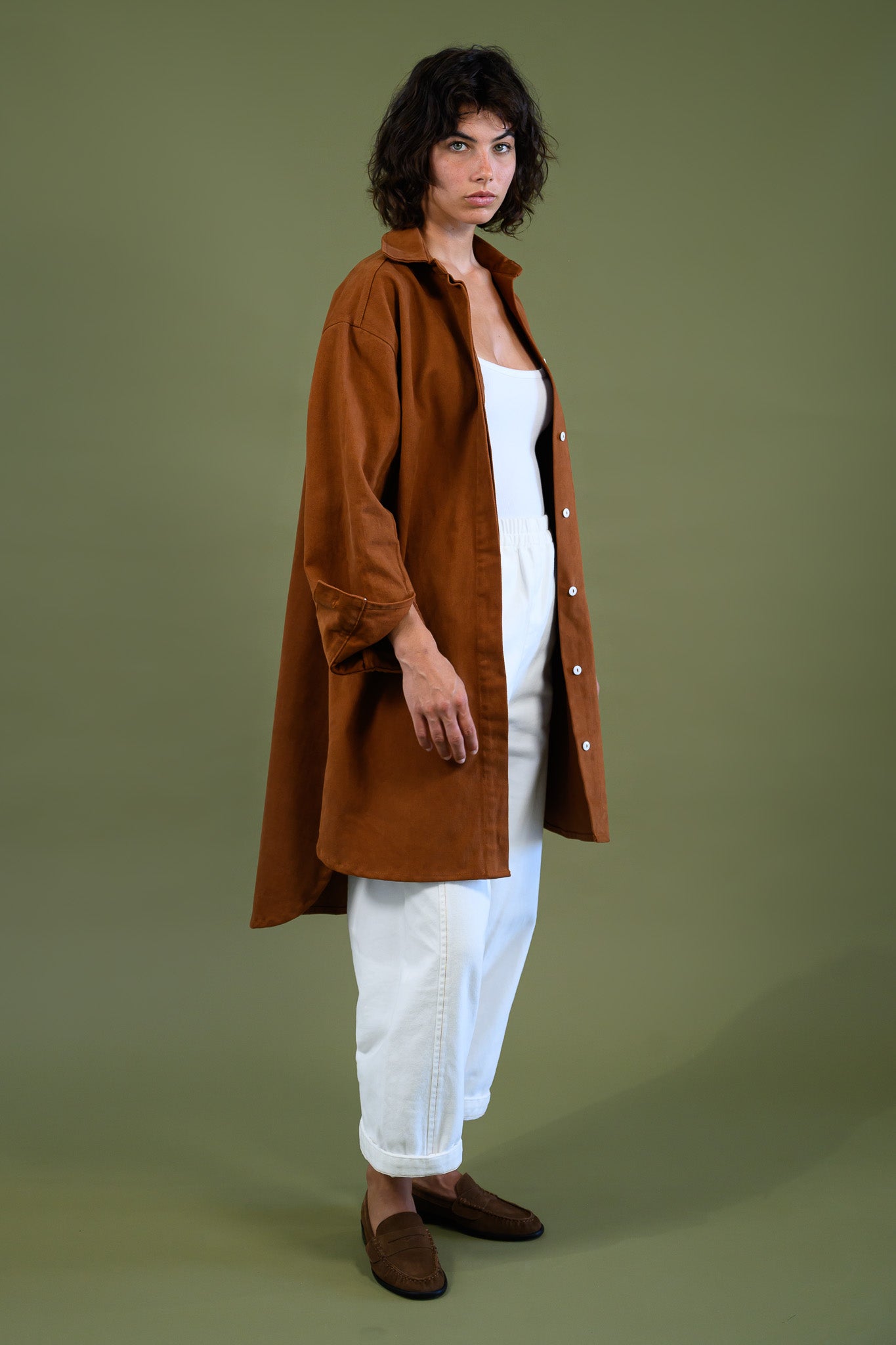 Side full body view of Caramel cotton canvas denim shirt coat worn open over white outfit