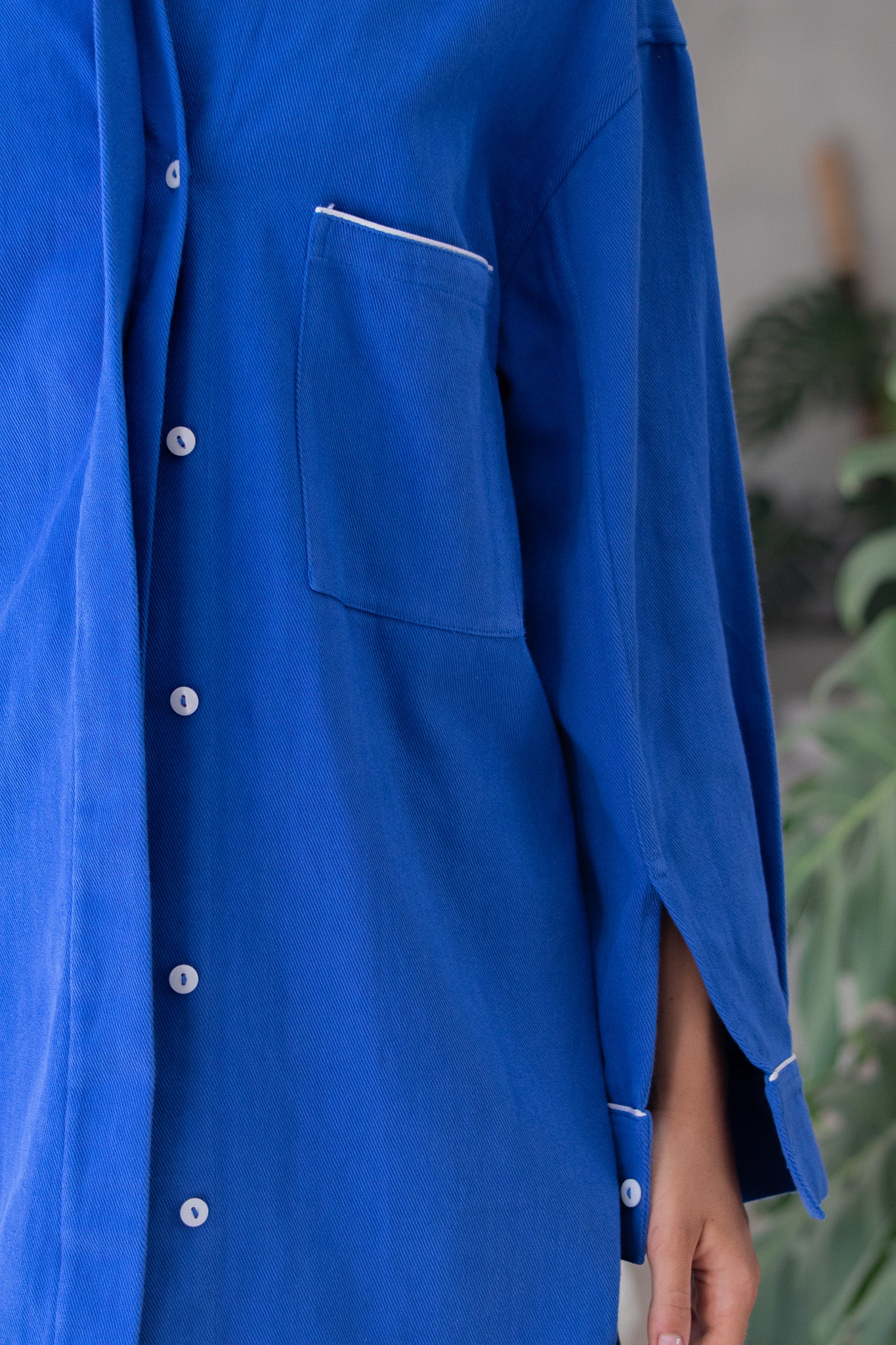 close pocket, button and cuff detail shot of denim blue jacket 