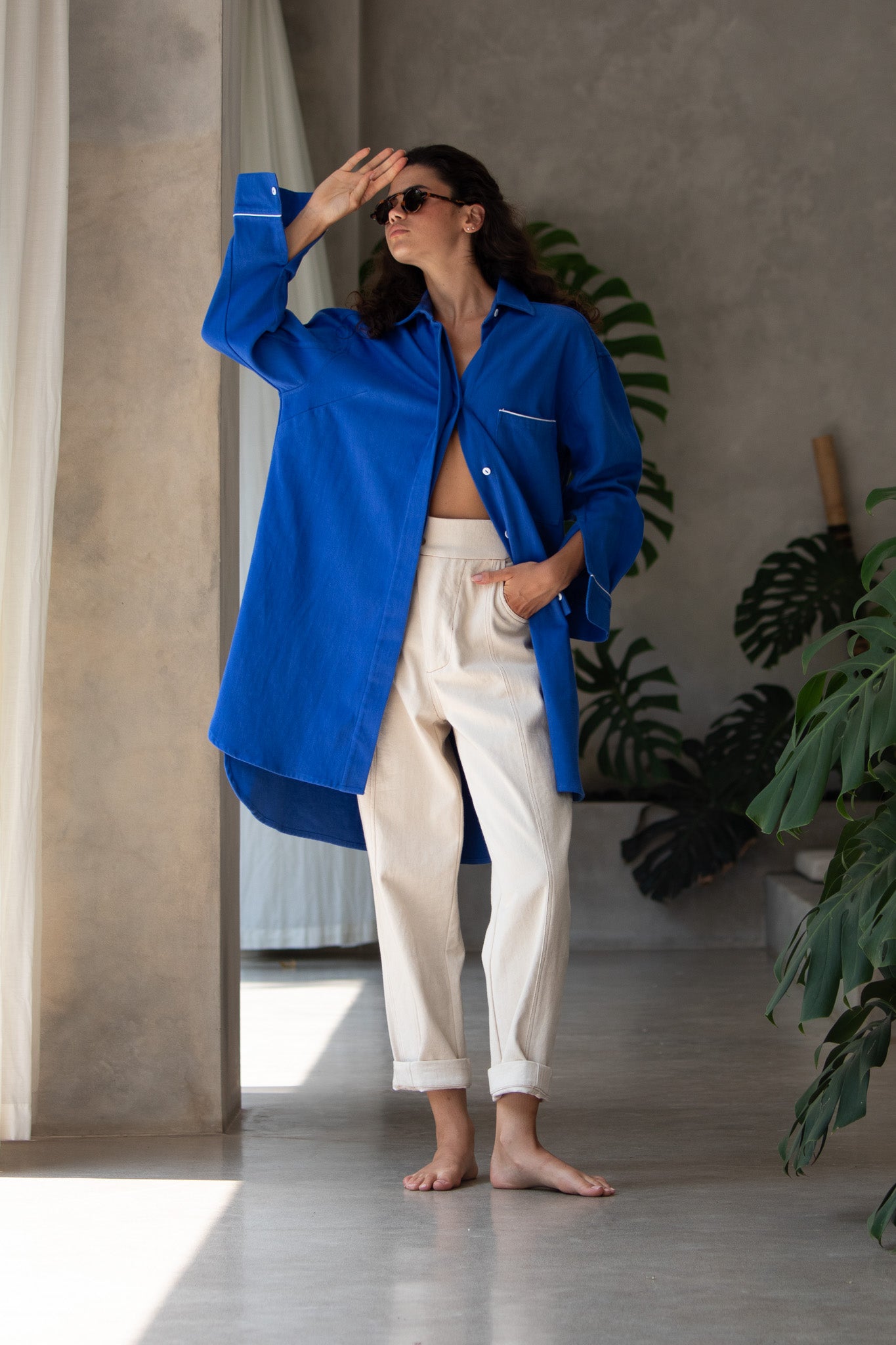 Model with jacket half open and hand on forehead, wearing denim blue jacket 