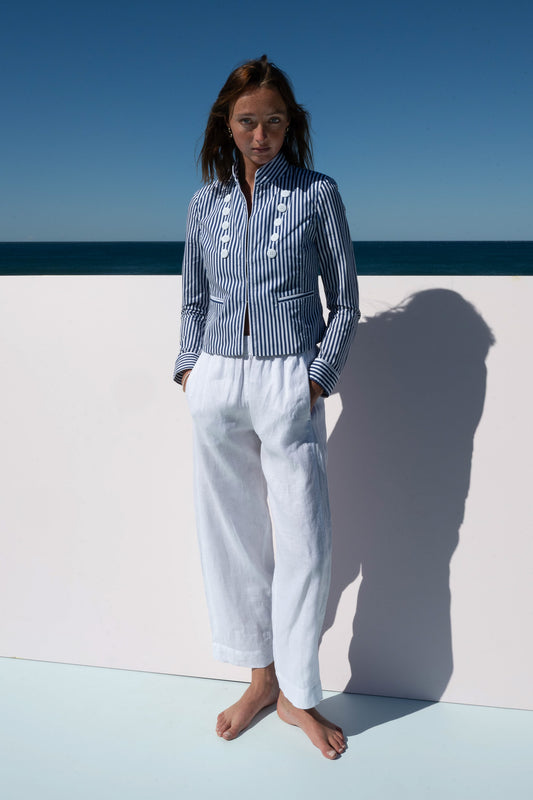 Full-length view of the Abbey Road Jacket styled with relaxed white linen pants, ocean in background.