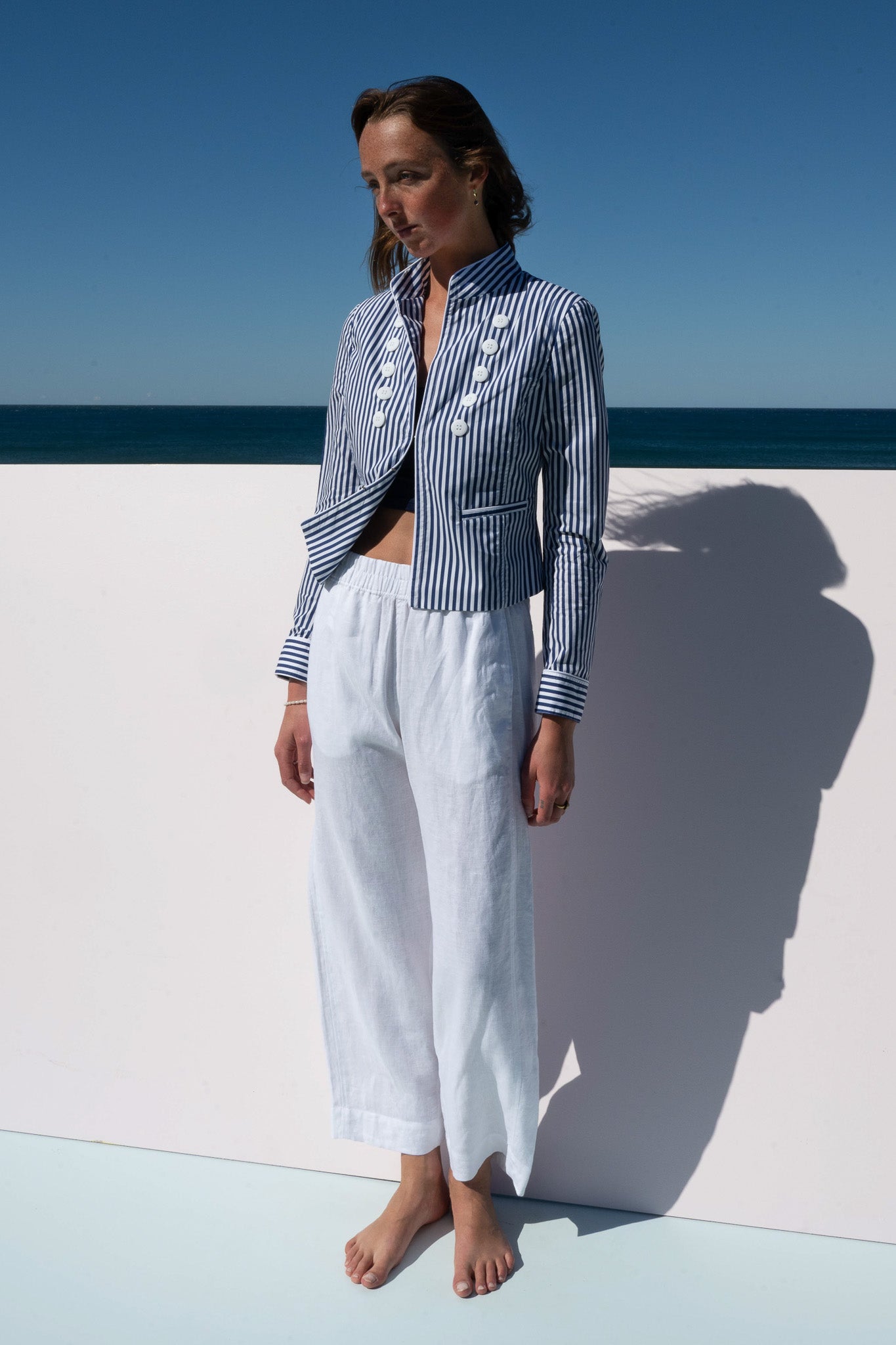 Model wearing the Abbey Road Jacket in azure stripe cotton poplin, relaxed stance with white linen pants.