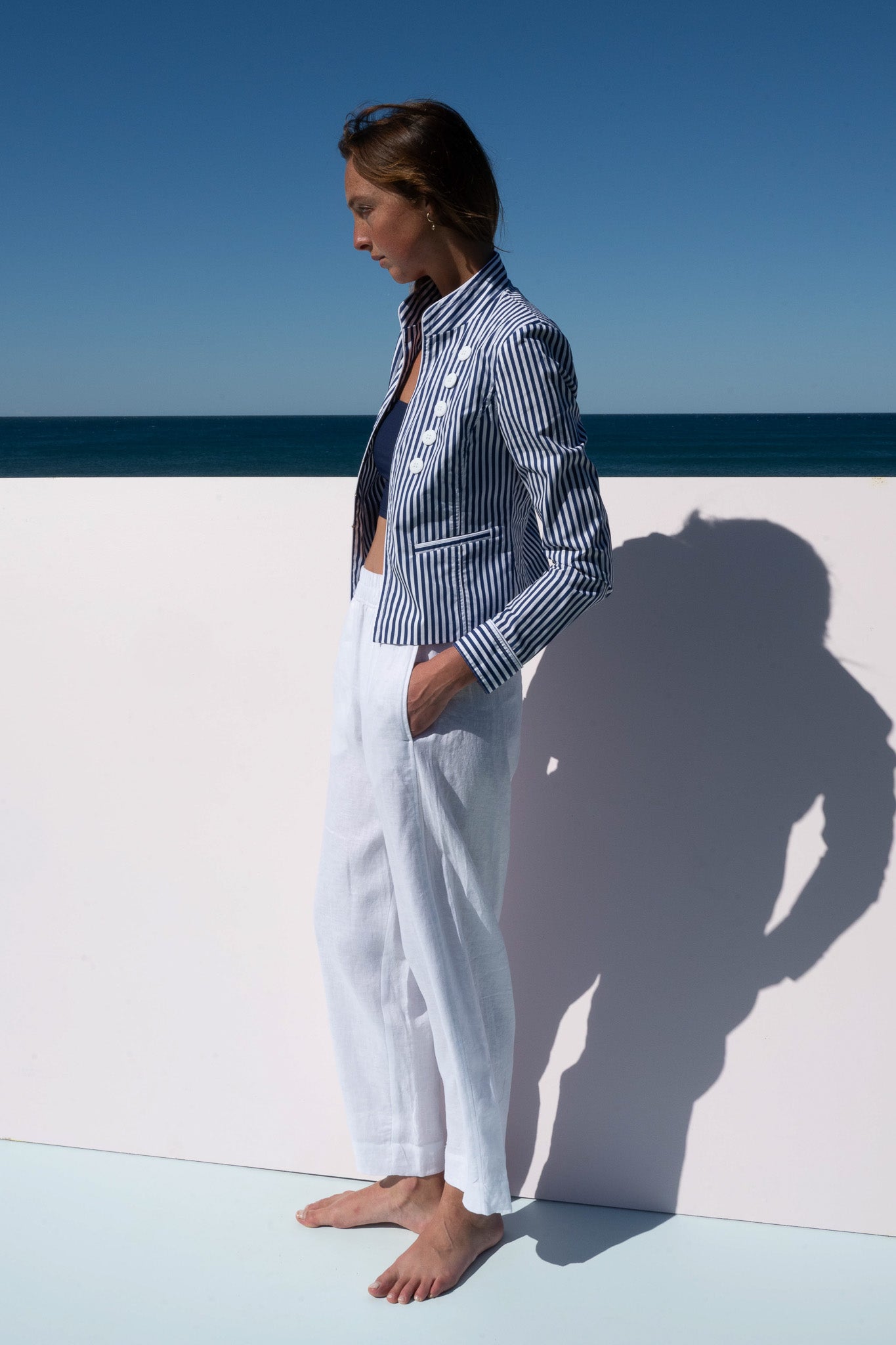 Side profile of Abbey Road Jacket in azure stripe cotton poplin styled with linen pants.