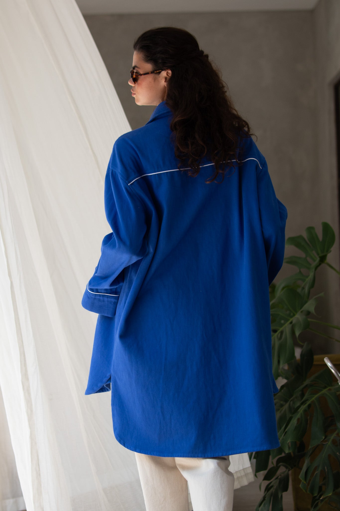 Back walking shot of model wearing denim blue jacket with binding 