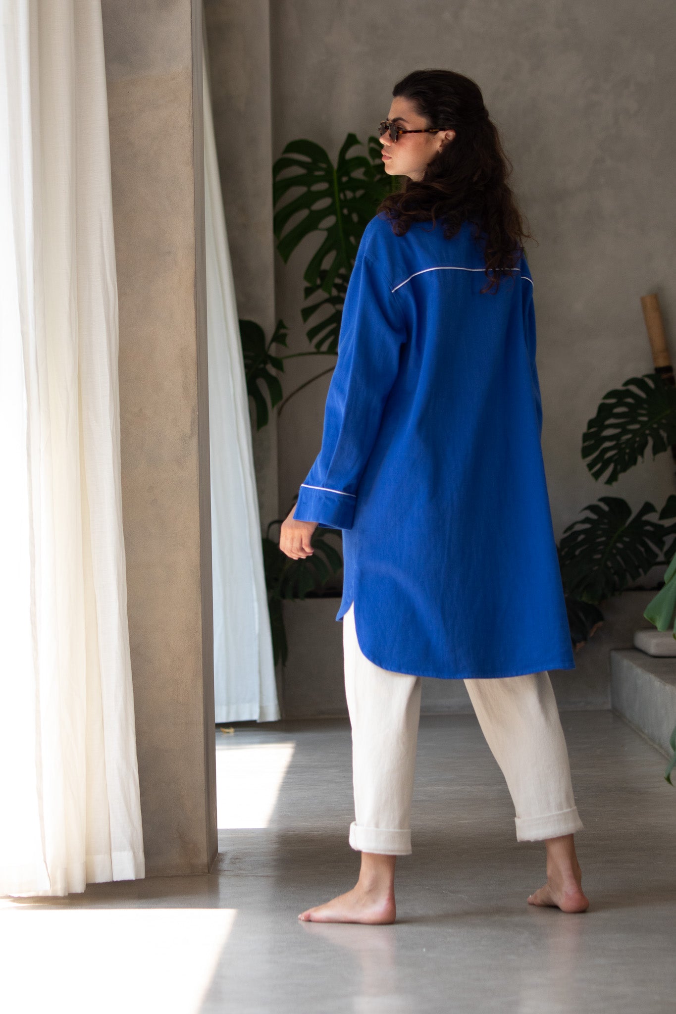 Back detail of denim blue jacket with white binding running across the back yoke and cuff