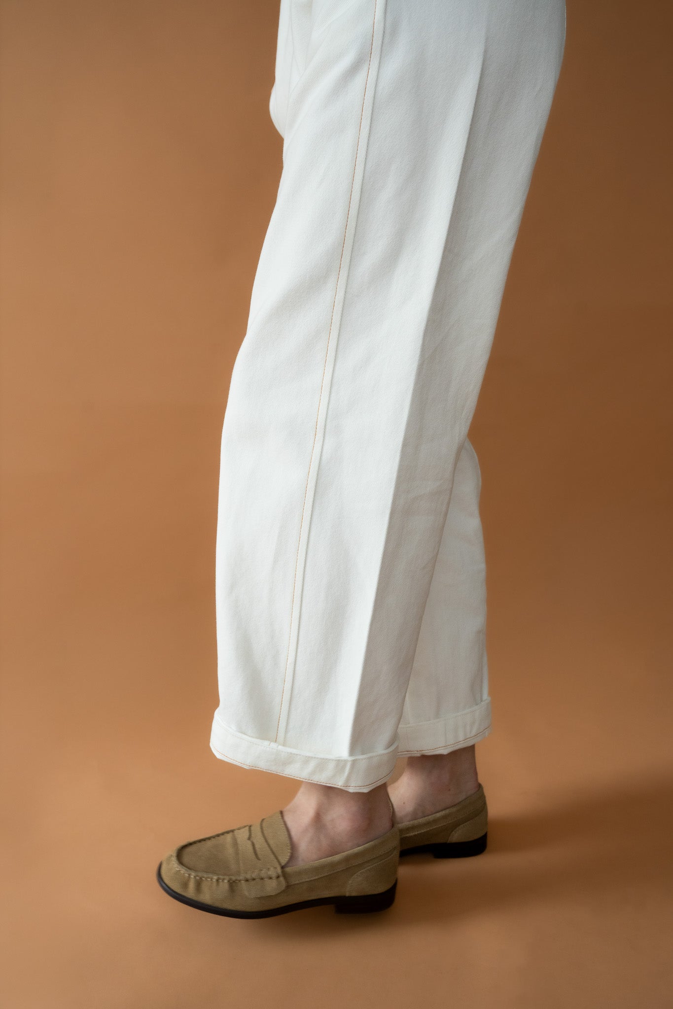Side angle view of Blaze Jogger pants in vanilla cotton twill with contrast burnt orange stitching
