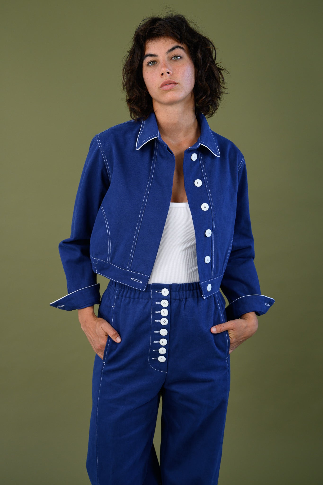 Blue cotton twill jacket with cropped fit and white contrast stitching shown full length on model