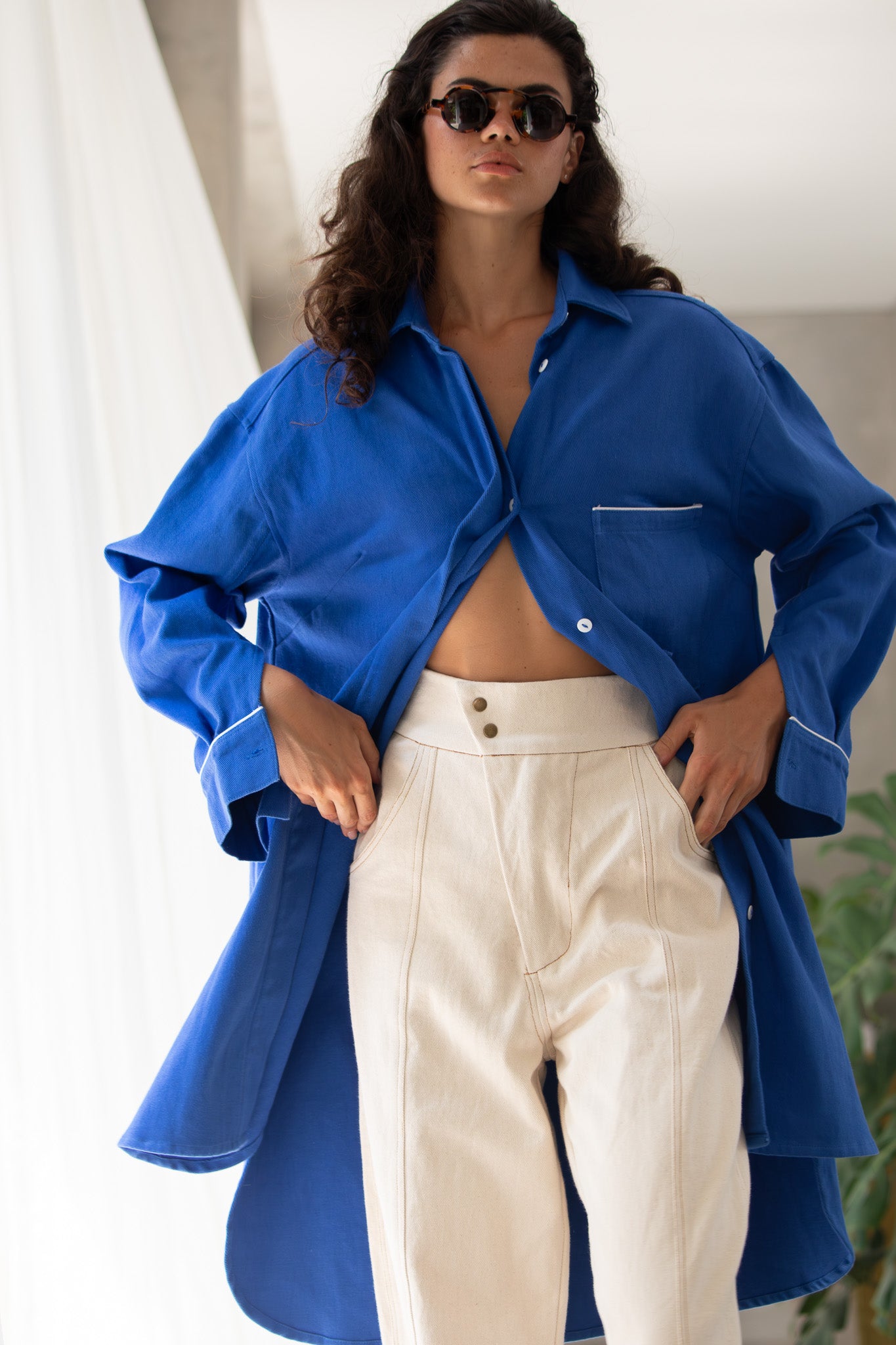 Model with half hands in her pocket showing detail of denim blue jacket and raw canvas pant 