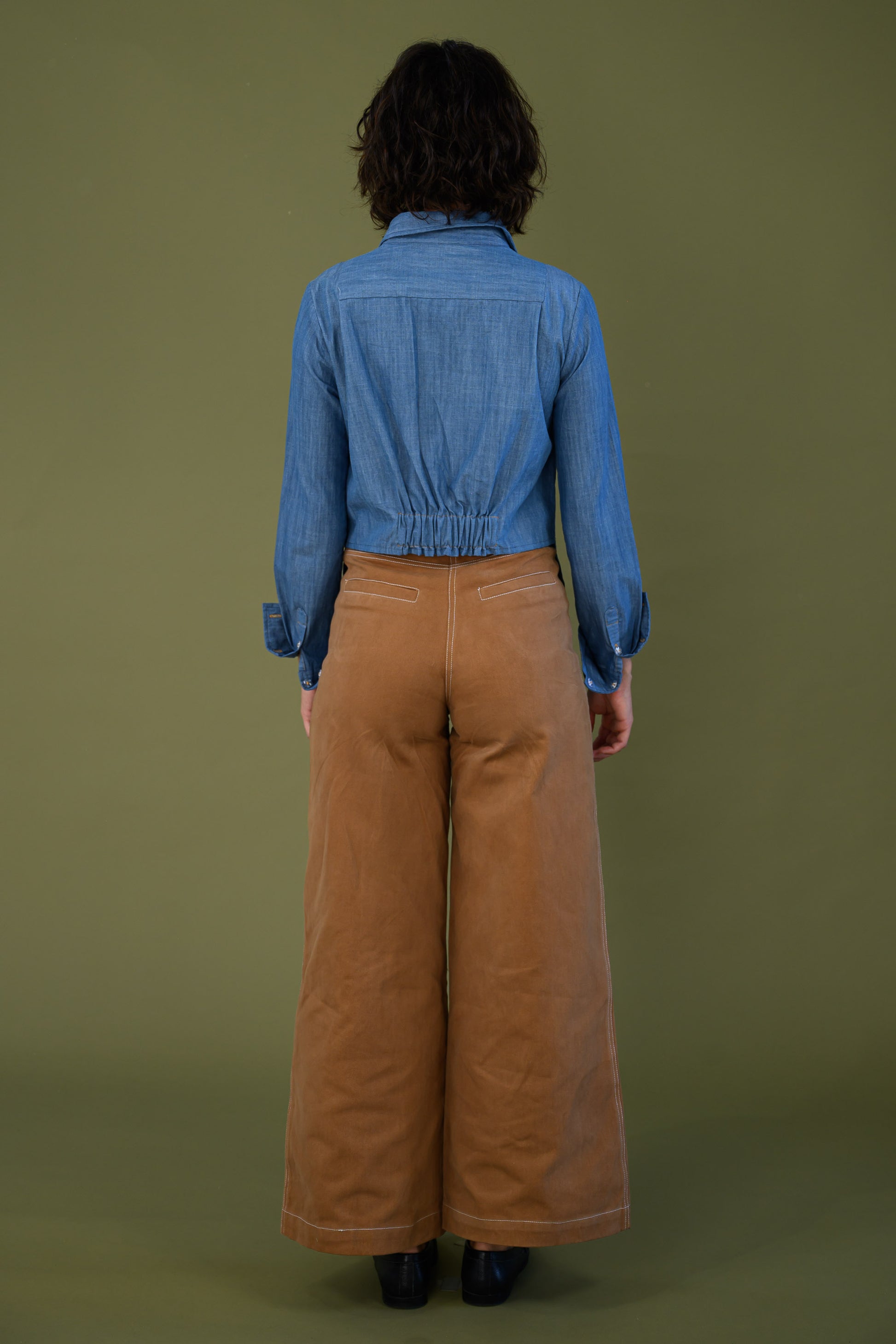 Back view of blue denim shirt showing cropped back and elasticated waist