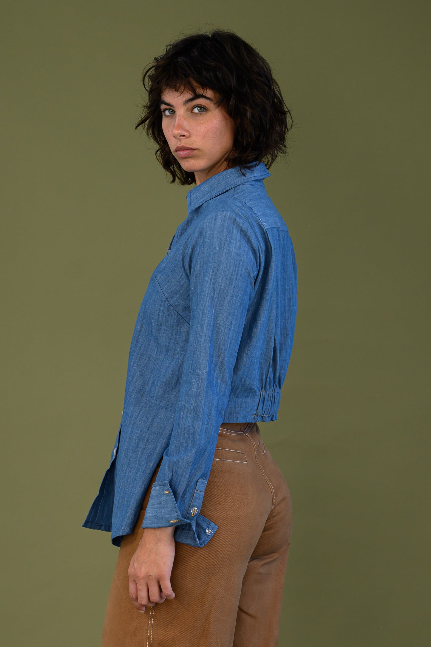 Side view of blue denim shirt showing cropped back and relaxed fit