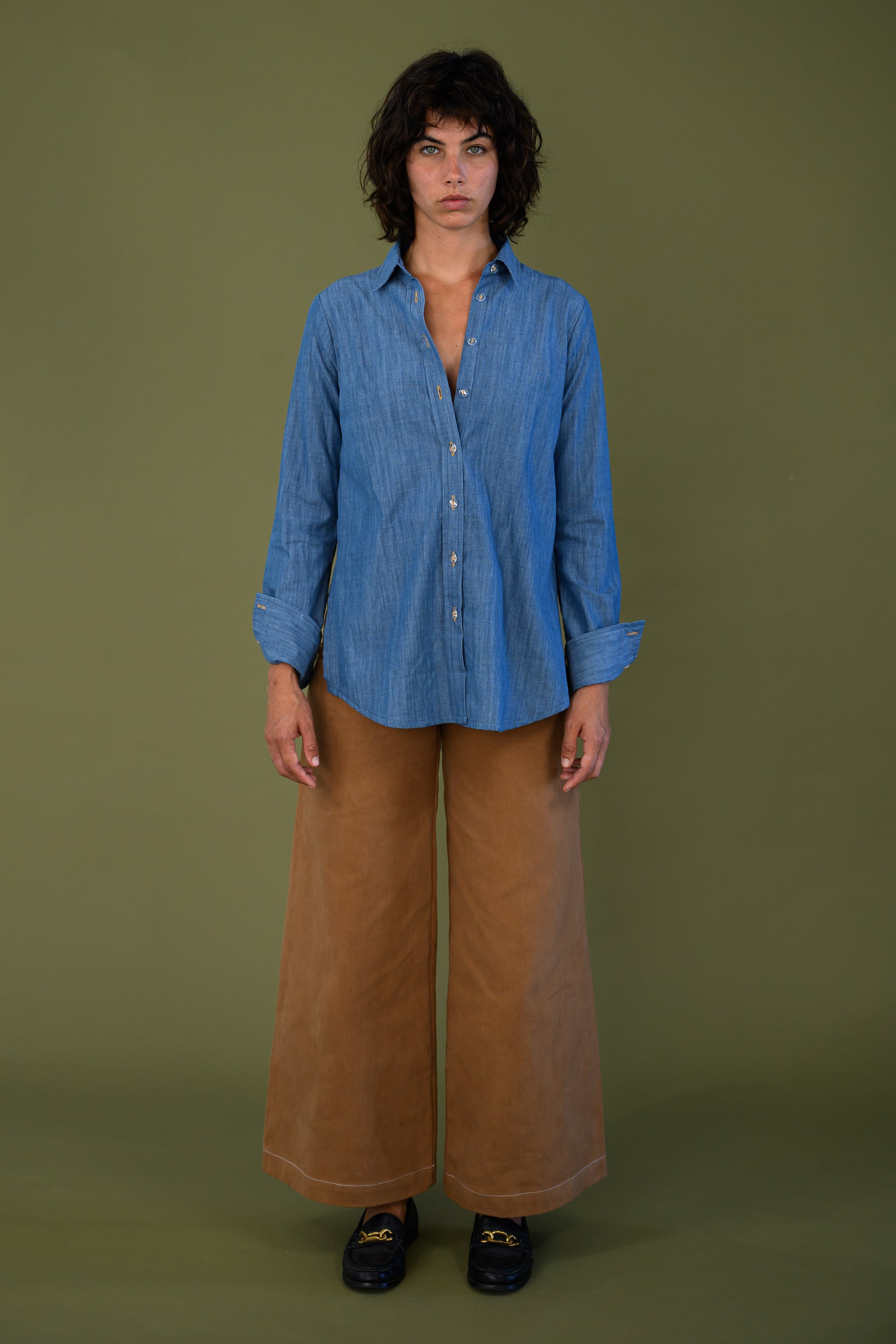 Blue denim shirt styled with brown pants shown full length on model