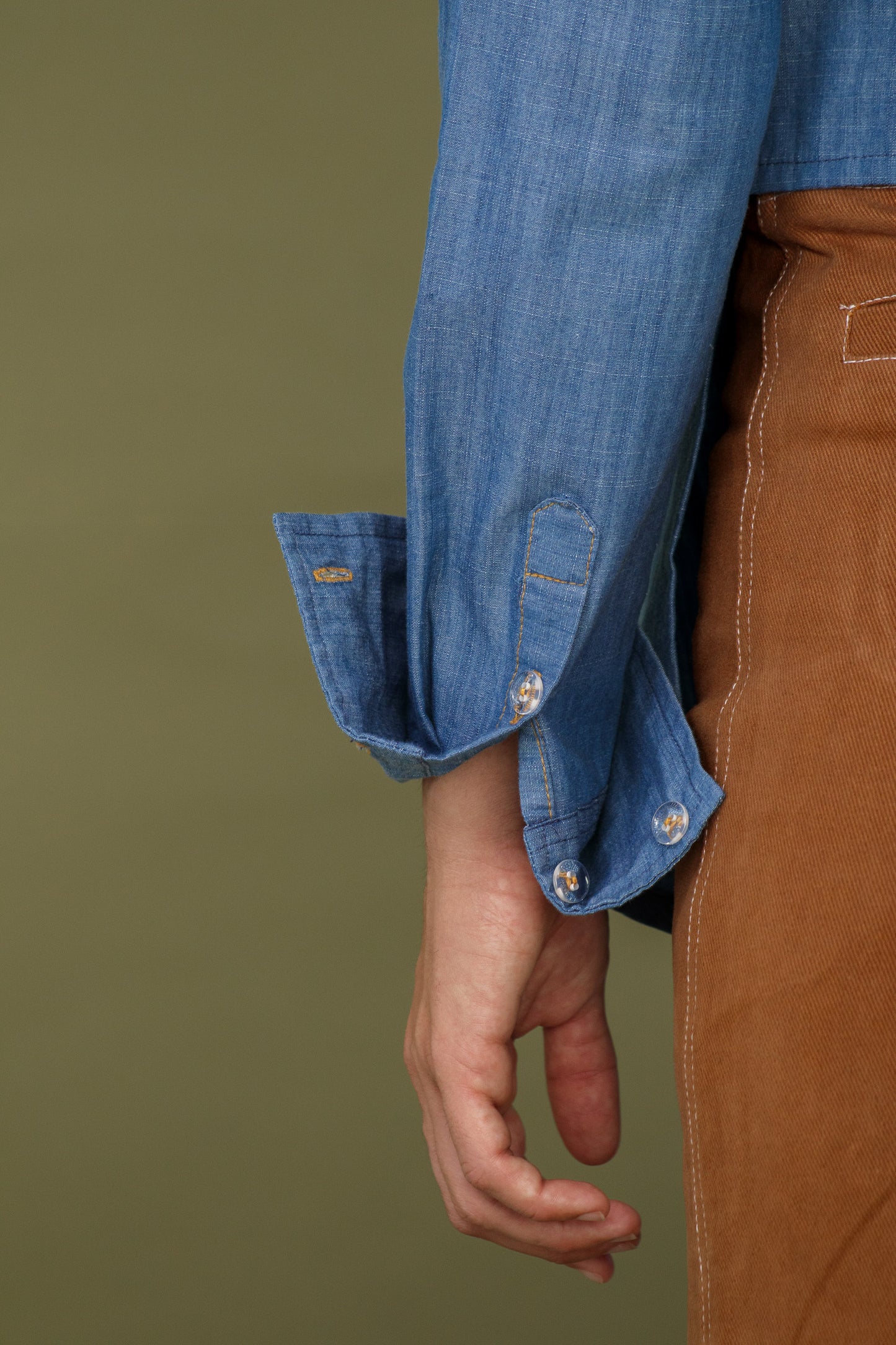 Close up of blue denim shirt sleeve showing stitching and cuff detail