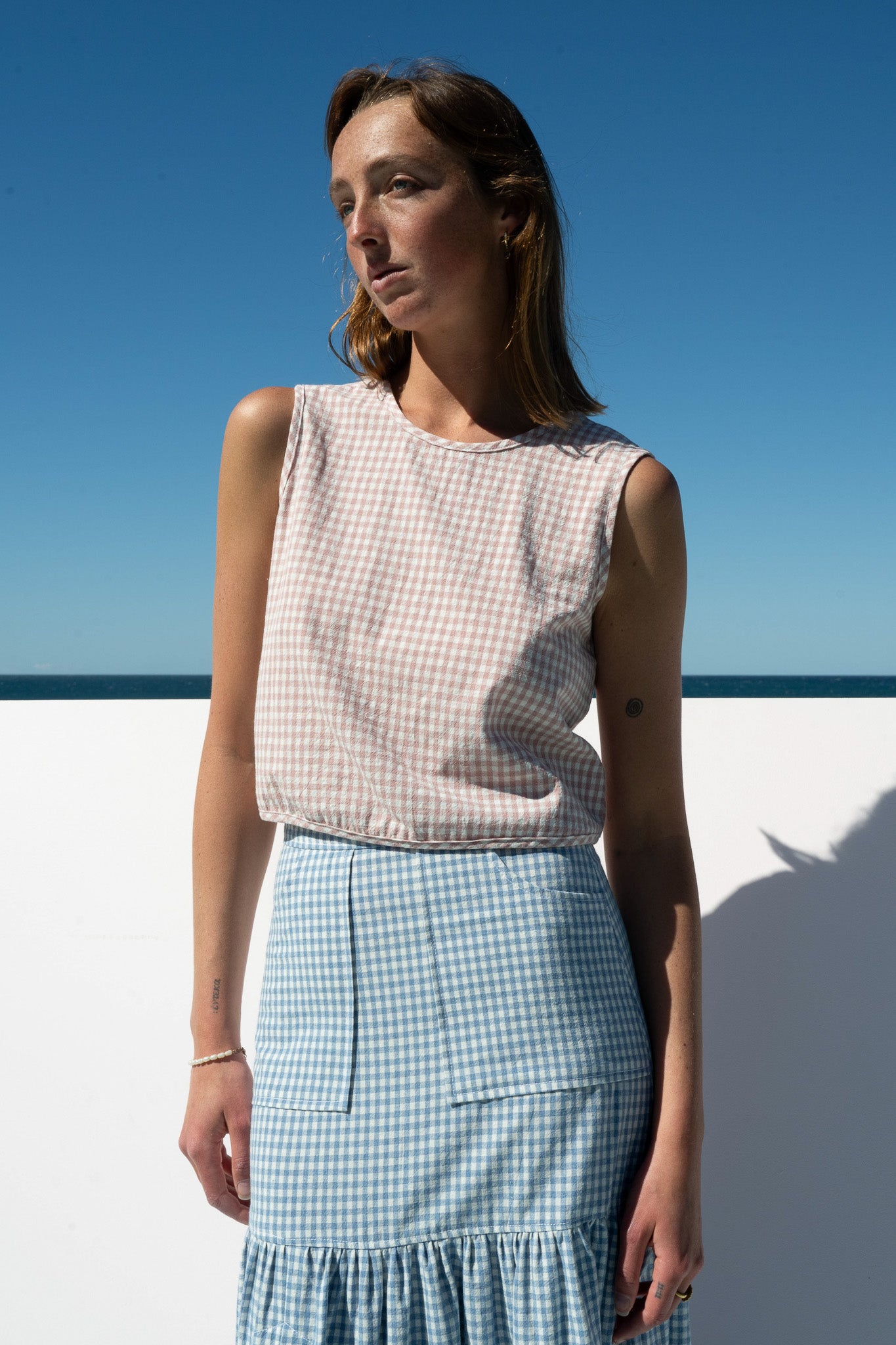 Front view of The Boy & I Box Crop Top in blush gingham paired with a blue gingham skirt