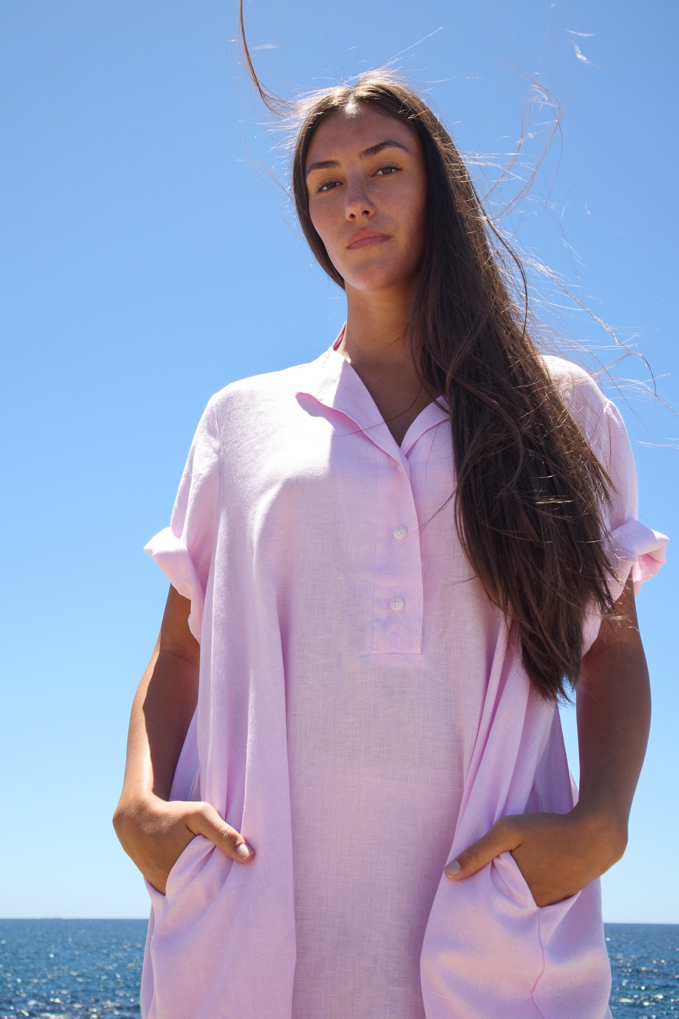 Close up of the Cabana Dress in bonbon pink showing the collar, buttons and texture in bright sunlight