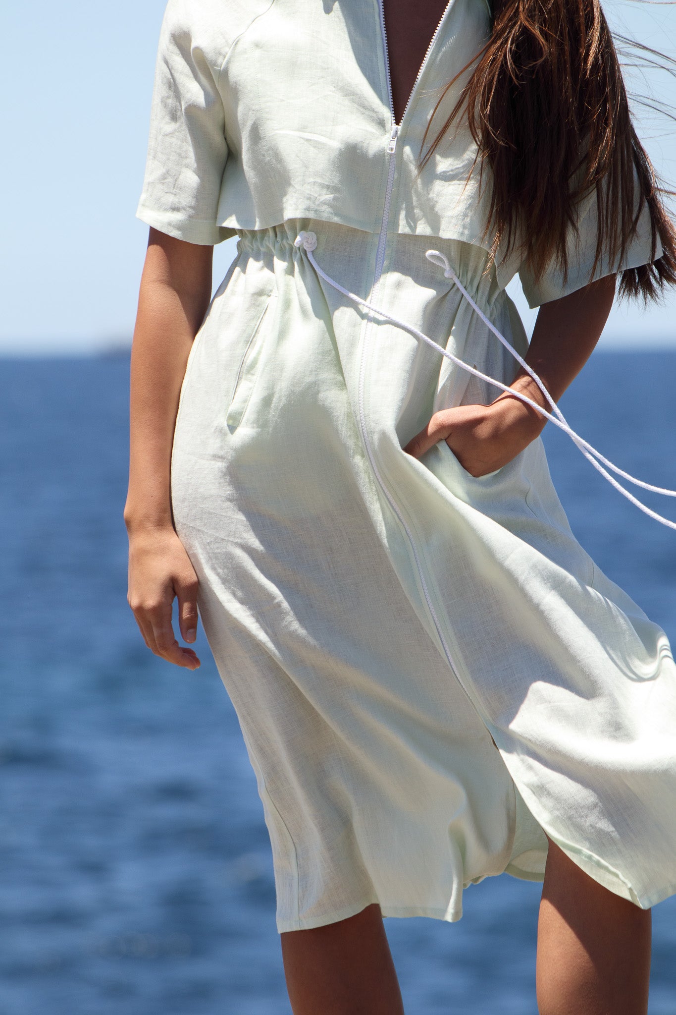 Close-up detail of the Iconica Dress drawcord waist and wide white zip, highlighting French linen texture and craftsmanship.