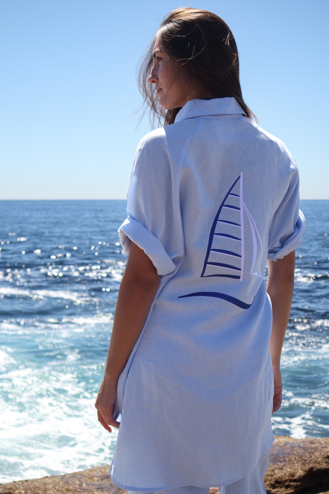 Side angle of the Oceanic Shirt in sail boat with embroidered sail detail and waves behind