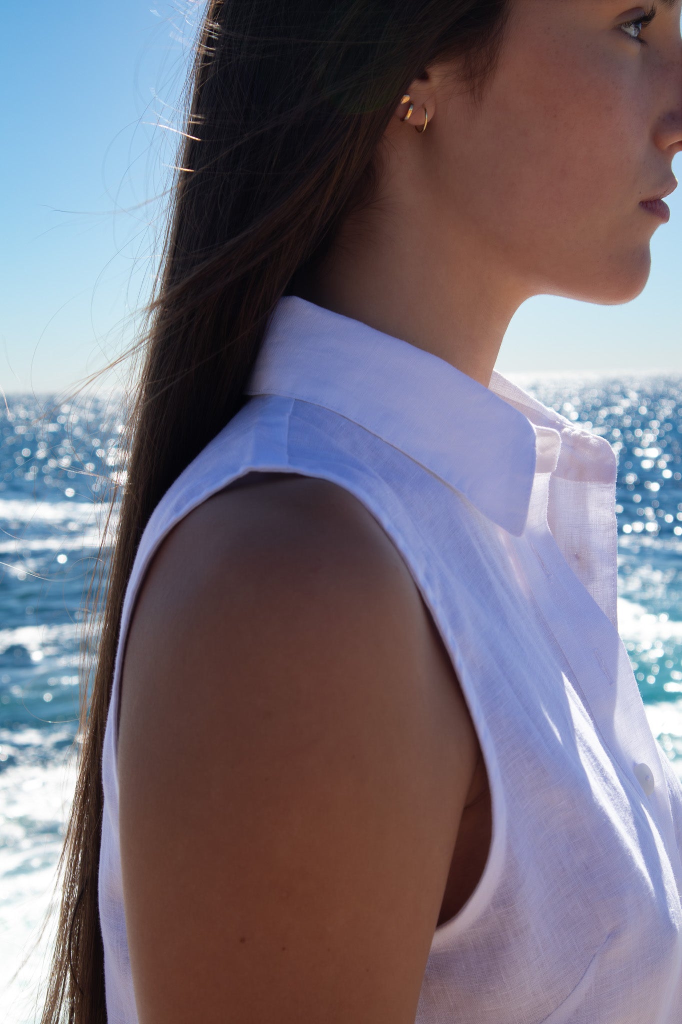 Close-up of the PEPE Top in white French flax linen showing the structured collar and sleeveless silhouette in natural sunlight by the ocean.