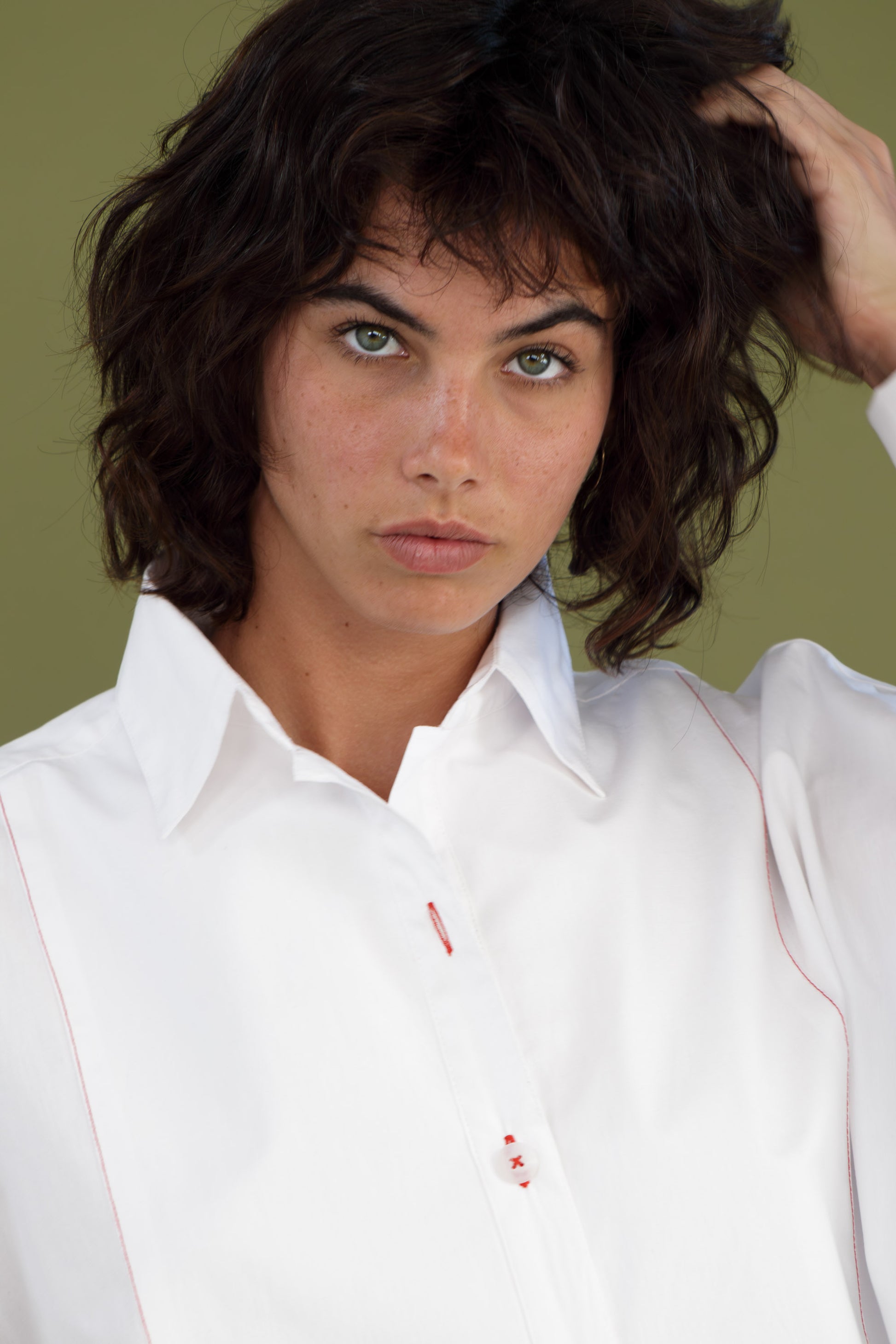 Close up portrait of oversized white boyfriend tux shirt in organic cotton poplin highlighting collar and button detail