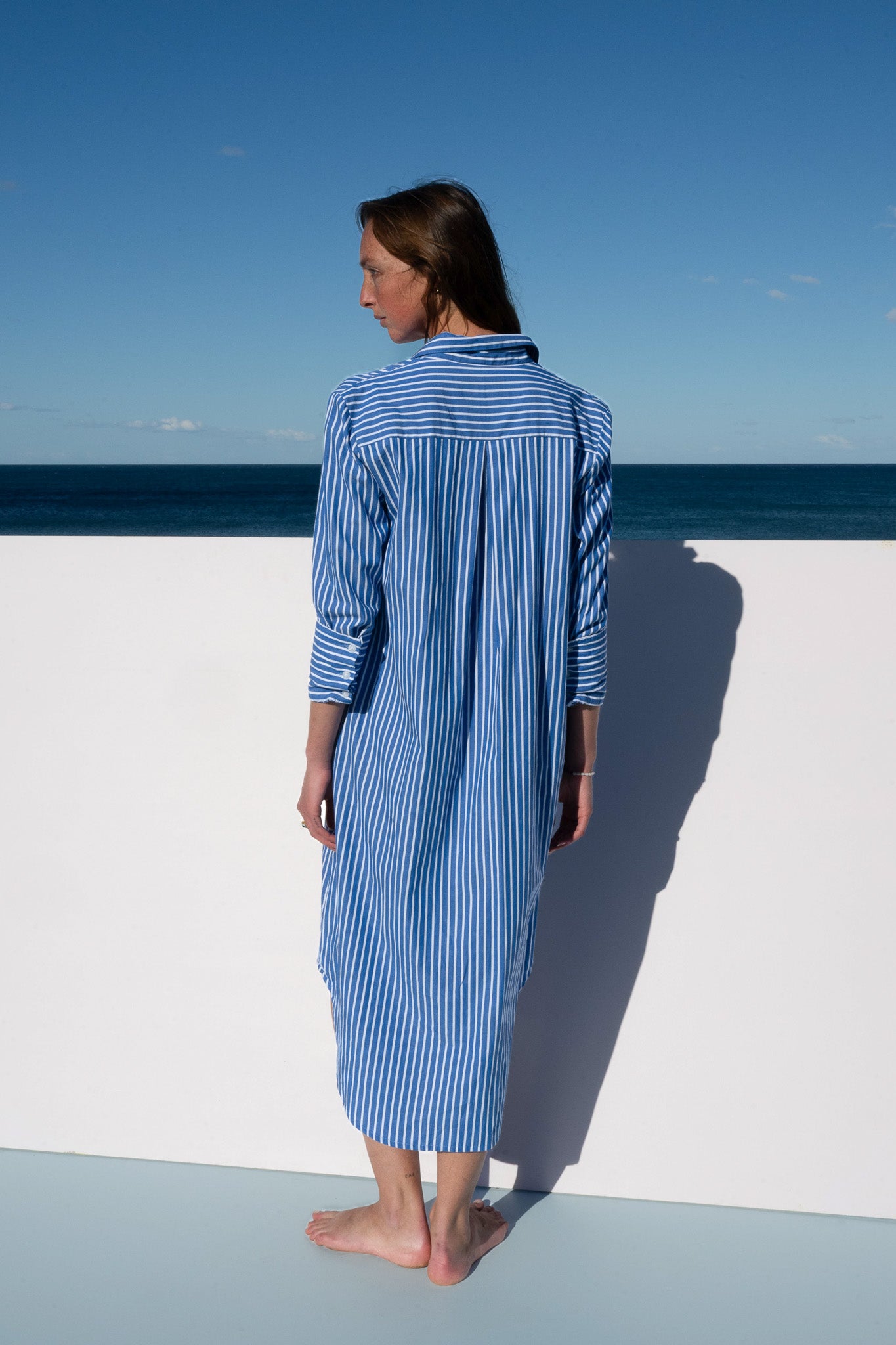 Full-length back view of The Boy & I Bronte Dress in blue and white pinstripe with straight hemline