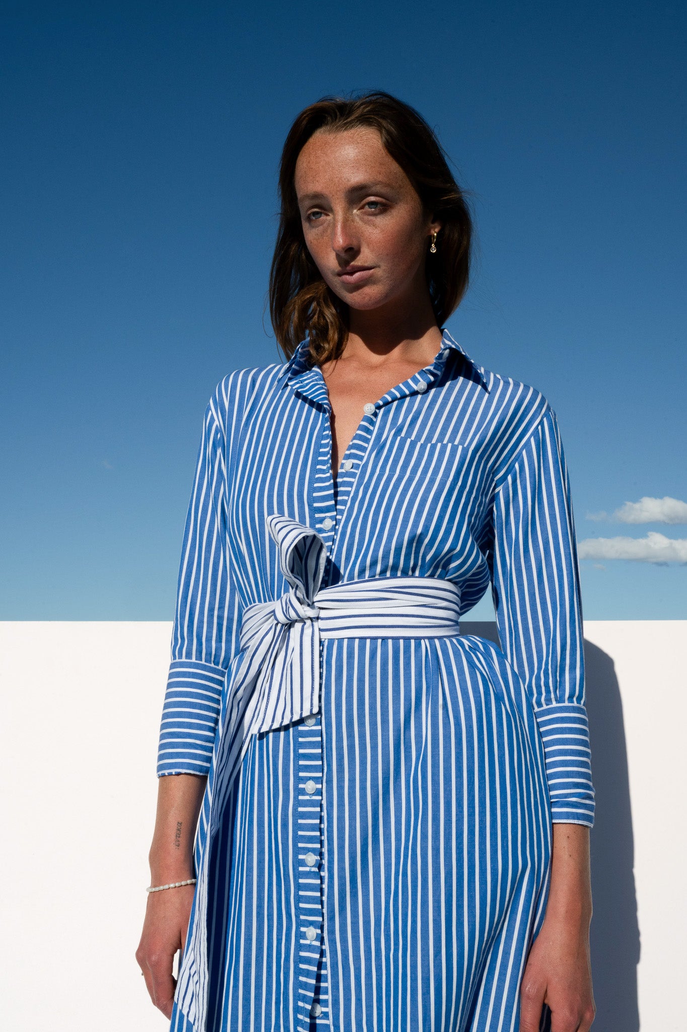 Model wearing The Boy & I Bronte Dress in blue and white pinstripe, styled with contrast waist tie