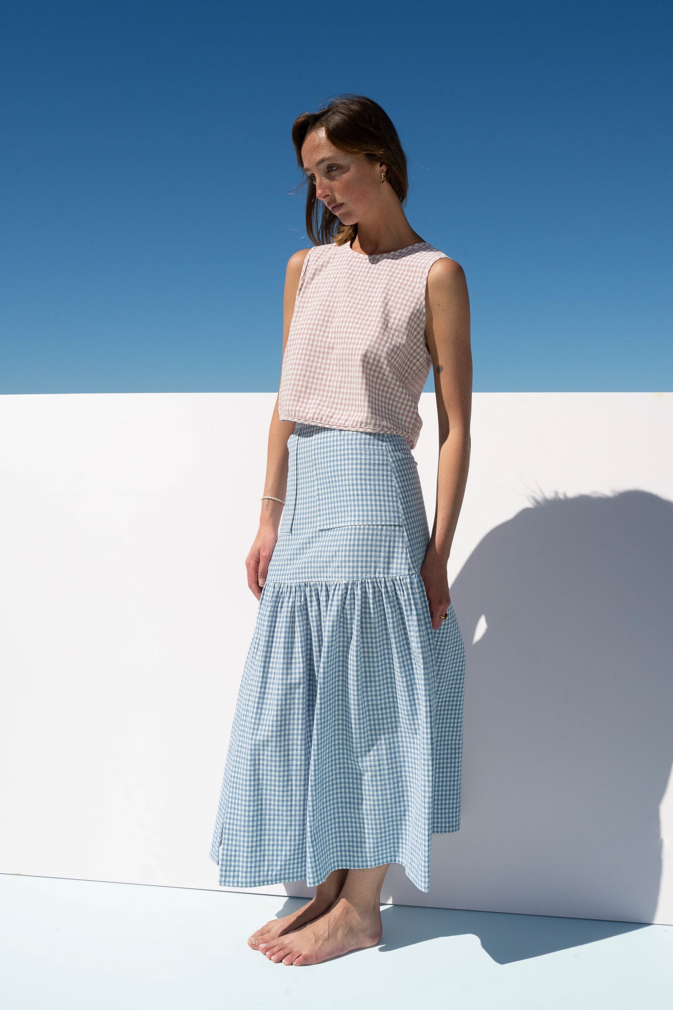Angled pose of Cancan Skirt blue gingham styled with blush gingham crop top