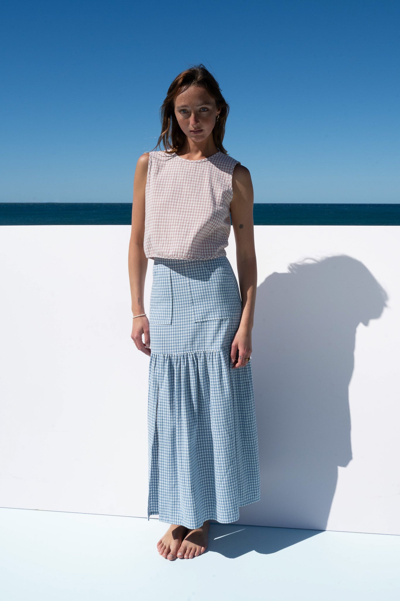 Straight-on portrait of model in Cancan Skirt blue gingham paired with blush gingham top.